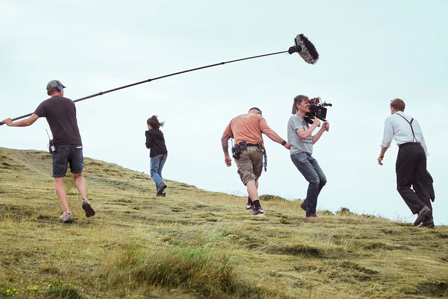 An actor walking up Arthur's Seat while being filmed by four crew members