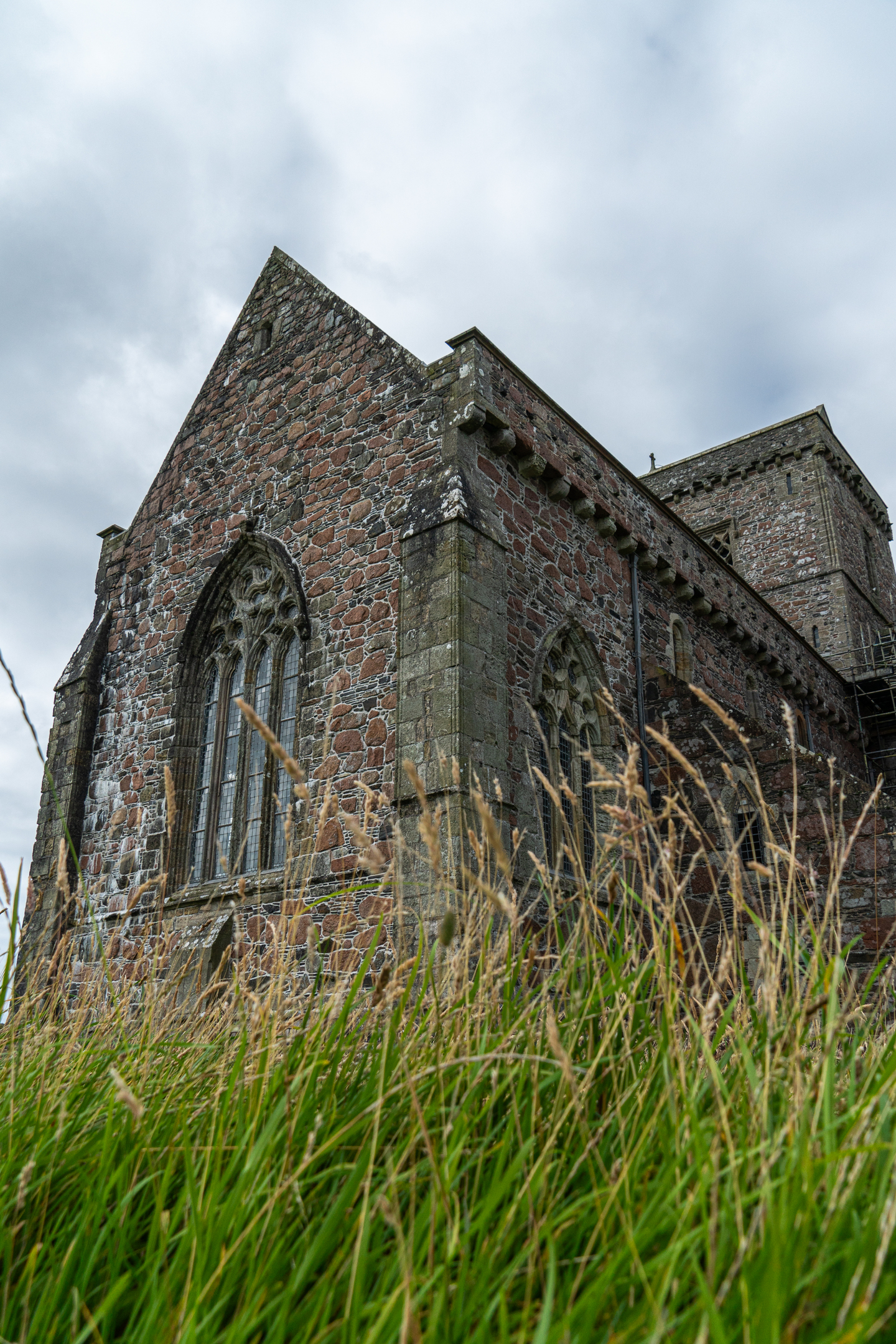 A historic stone abbey with long grass in front of it