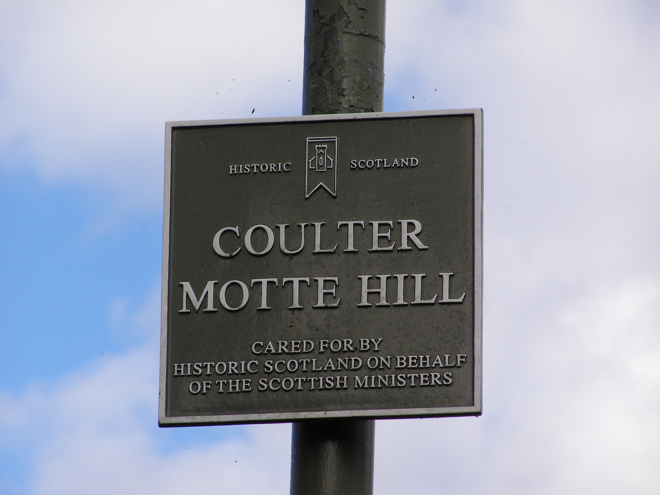 A retro metal sign marking the site of Coulter Motte Hill. The sign features the Historic Scotland logo. 