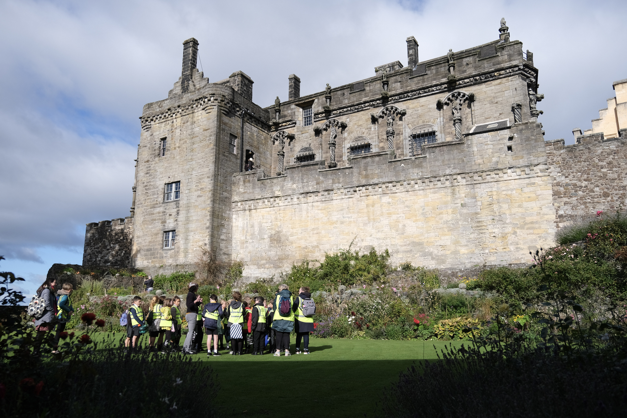 Group of school pupils in garden area beneath imposing castle