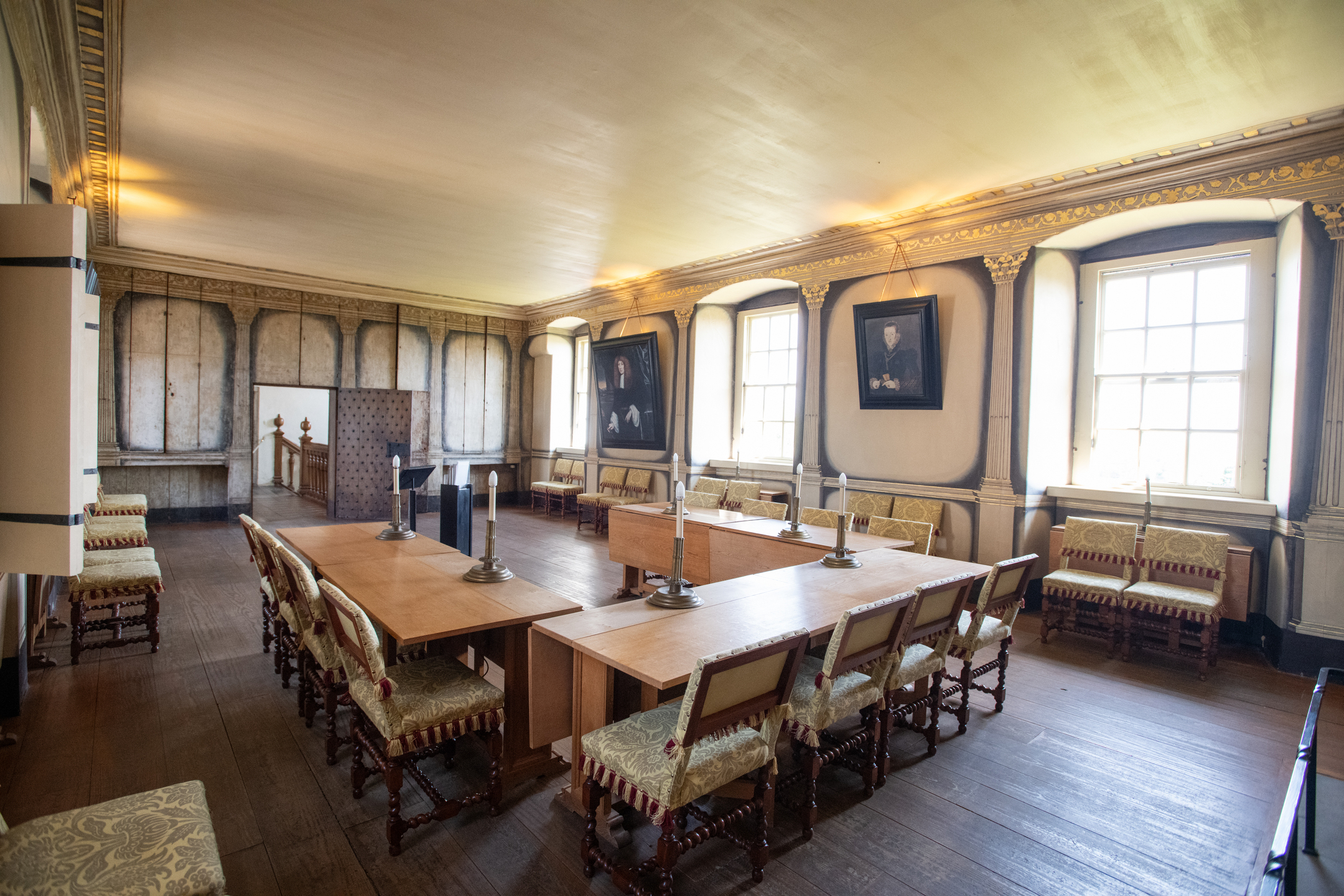 A large and ornate room in a historic townhouse. Portraits hang on the walls.