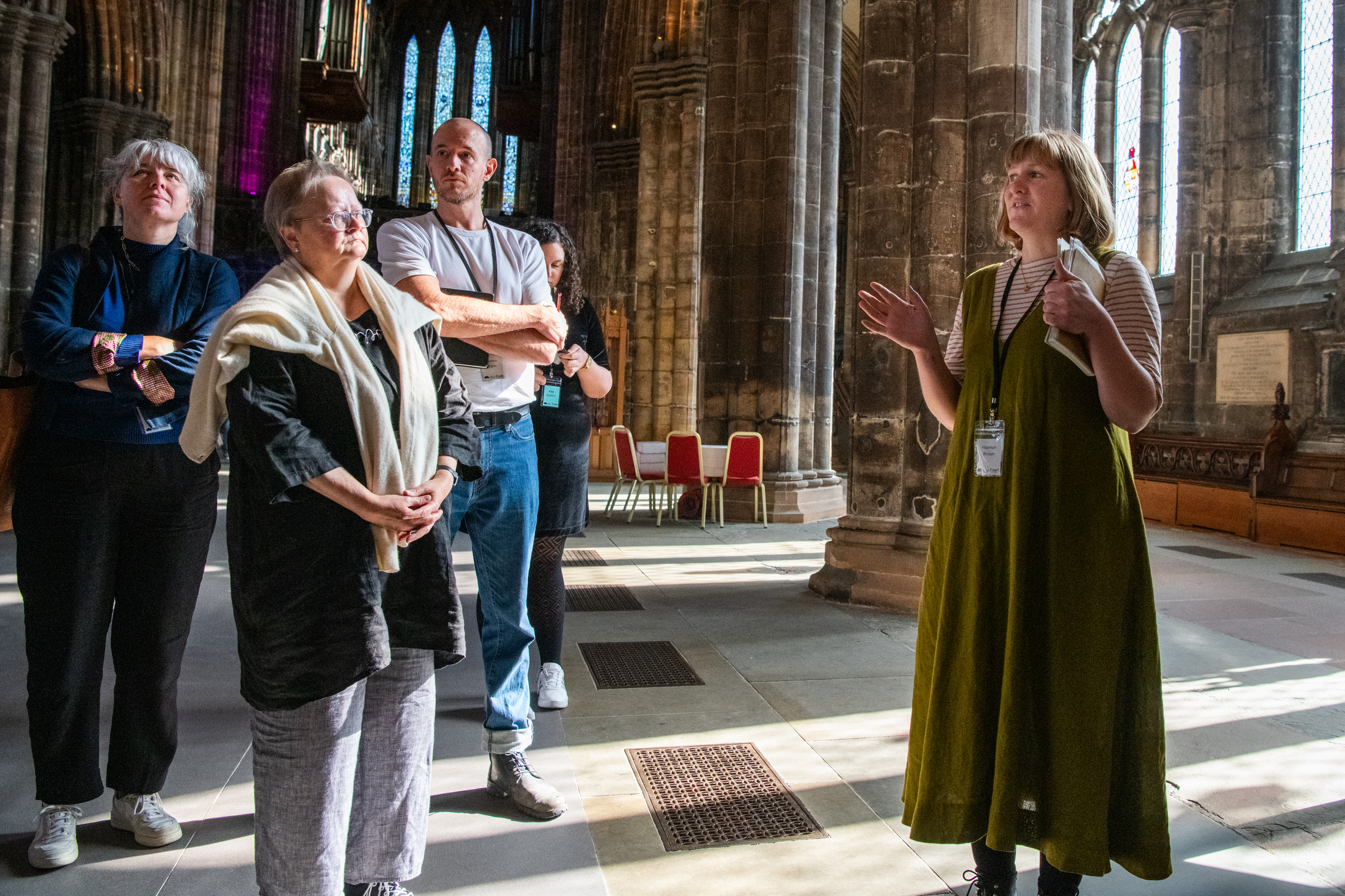 A group of visitors listen to a guide as they take a tour of Glasgow Cathedral.