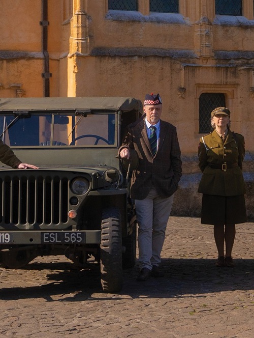 Reenactor walking next to a wartime car.