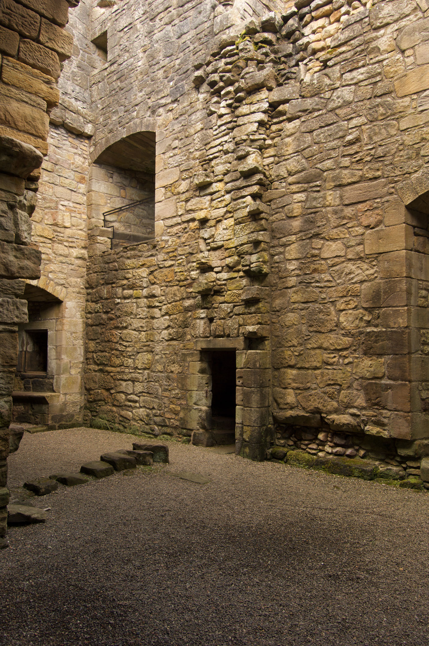 Stone courtyard with doorways and high walls inside castle ruins.