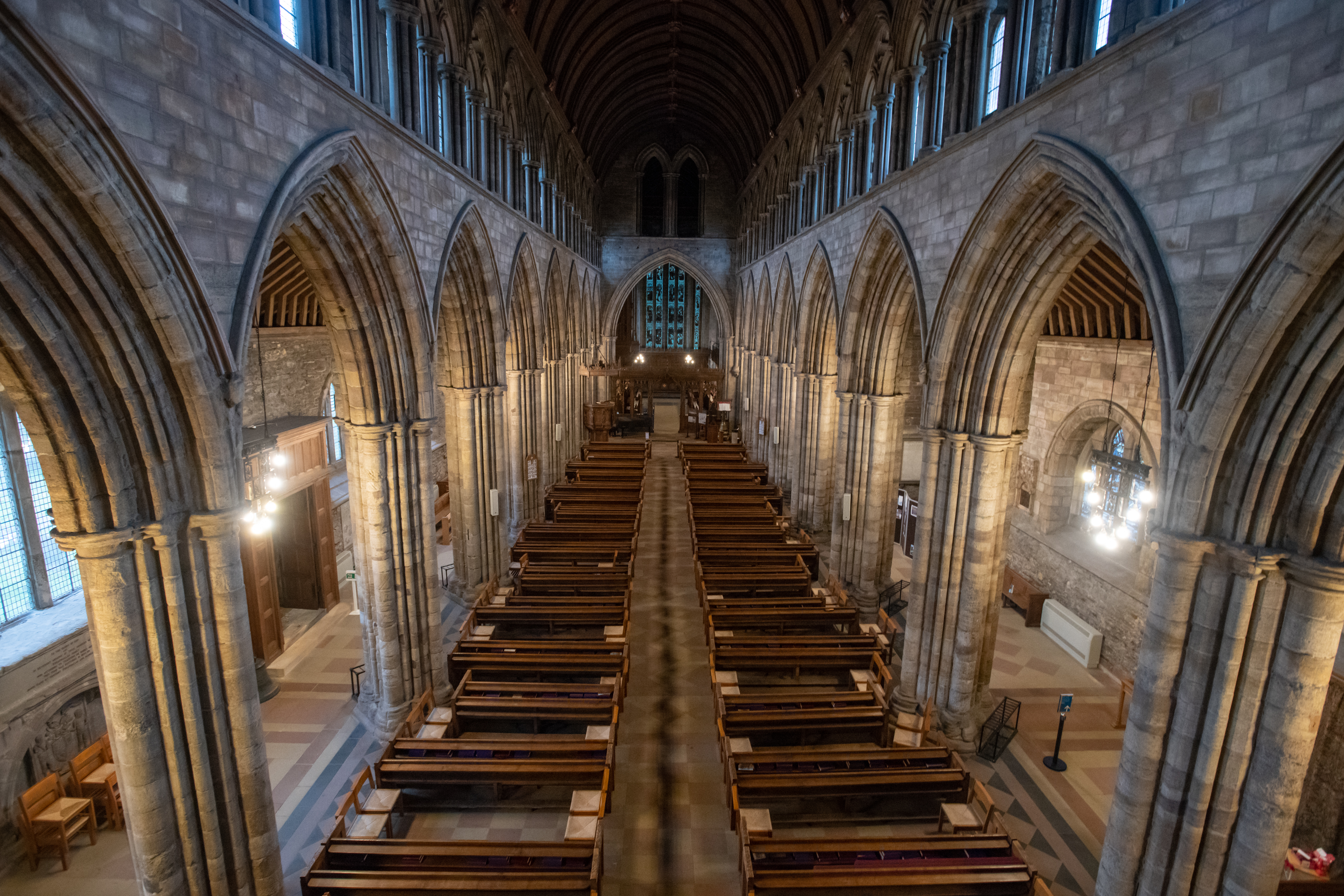 Interior of a cathedral with columns, pews and a high arched roof. 