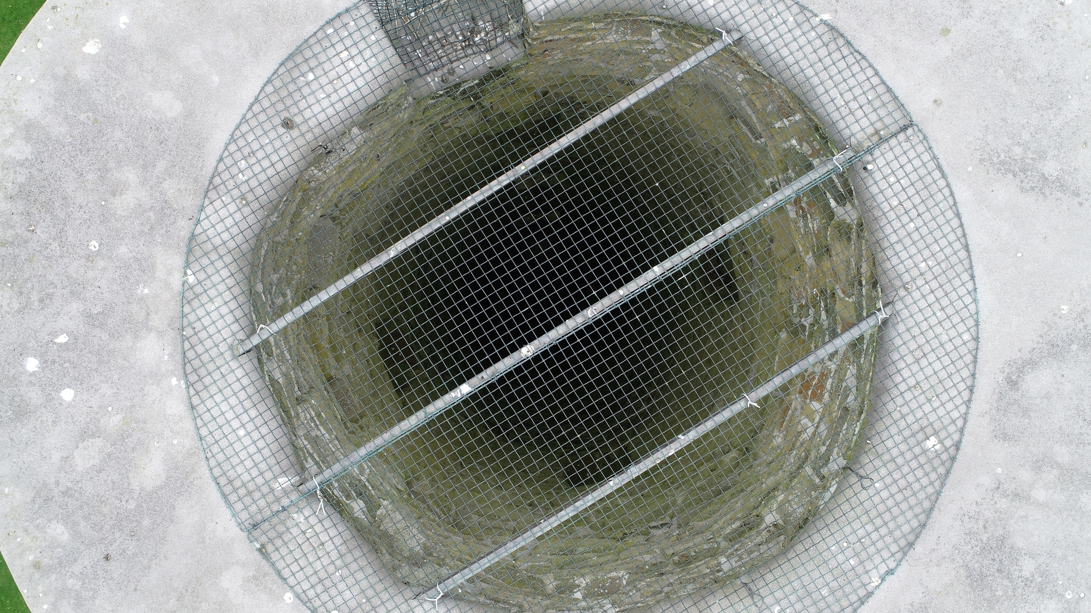 Top‑down view of the round tower interior covered by a metal safety grille at the opening.