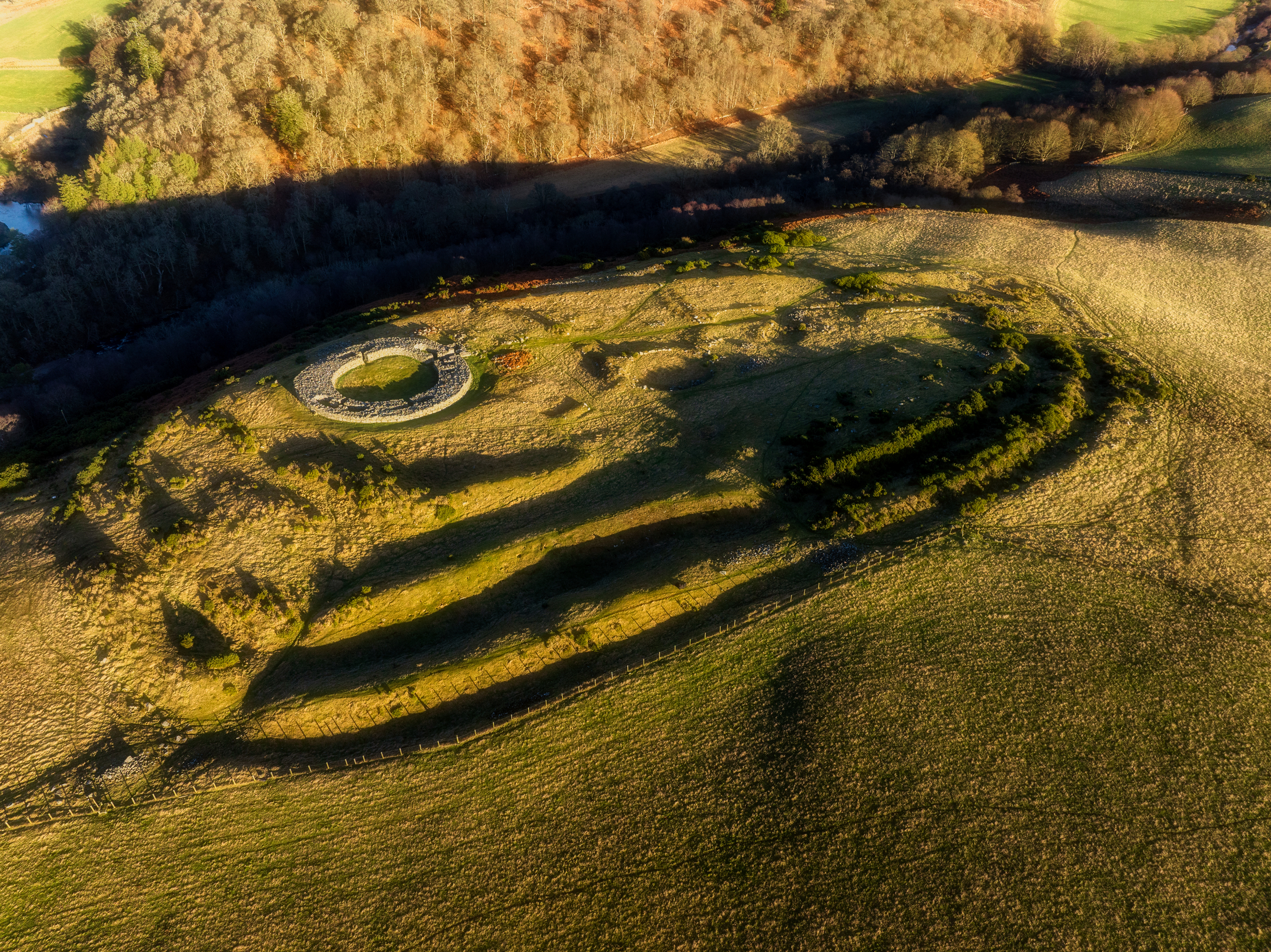Far away bird's eye view of Edin's Hall Iron Age Broch and grassy surroudings and the tiered mound 
