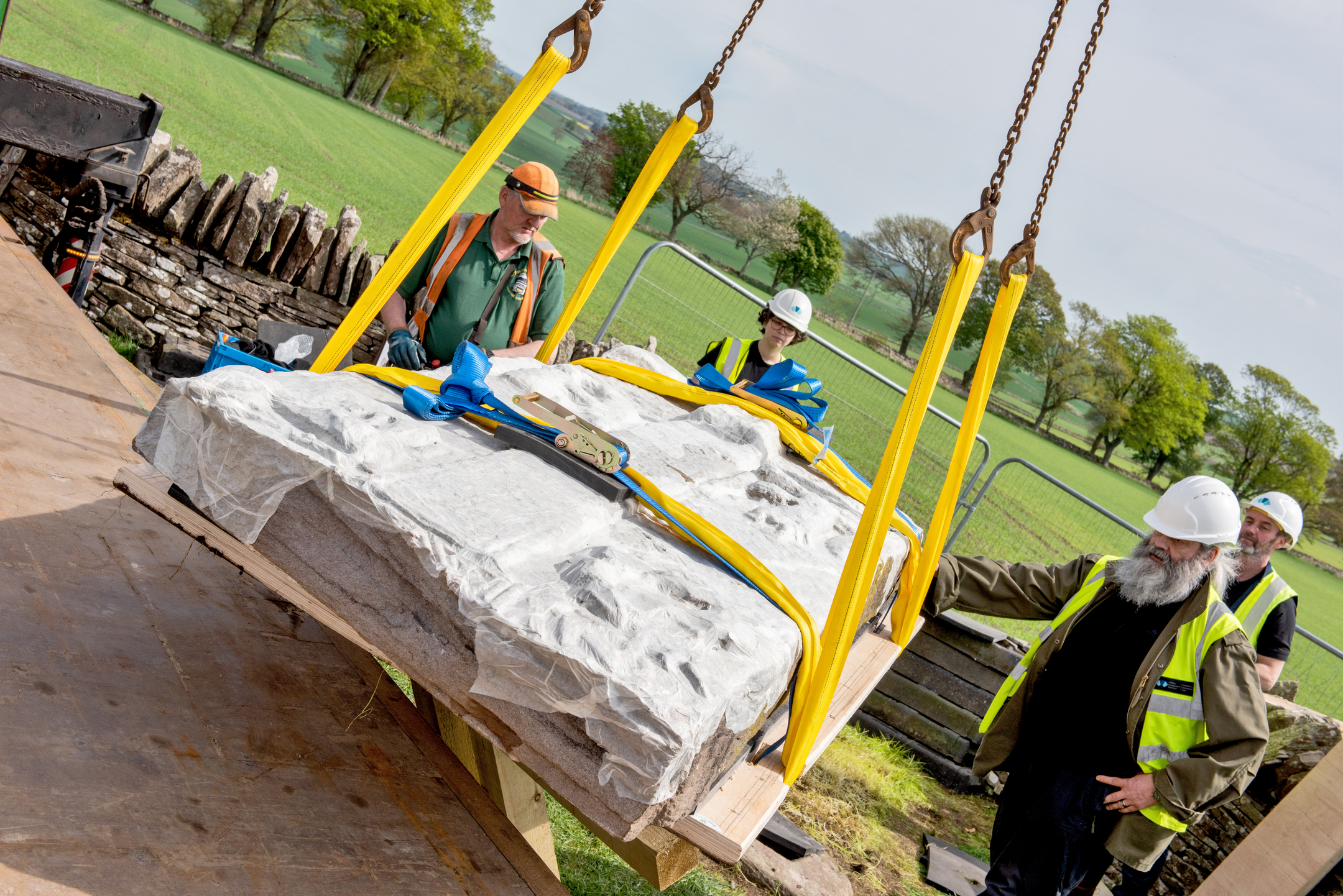 A carved stone is carefully lifted using a crane and protective covering.