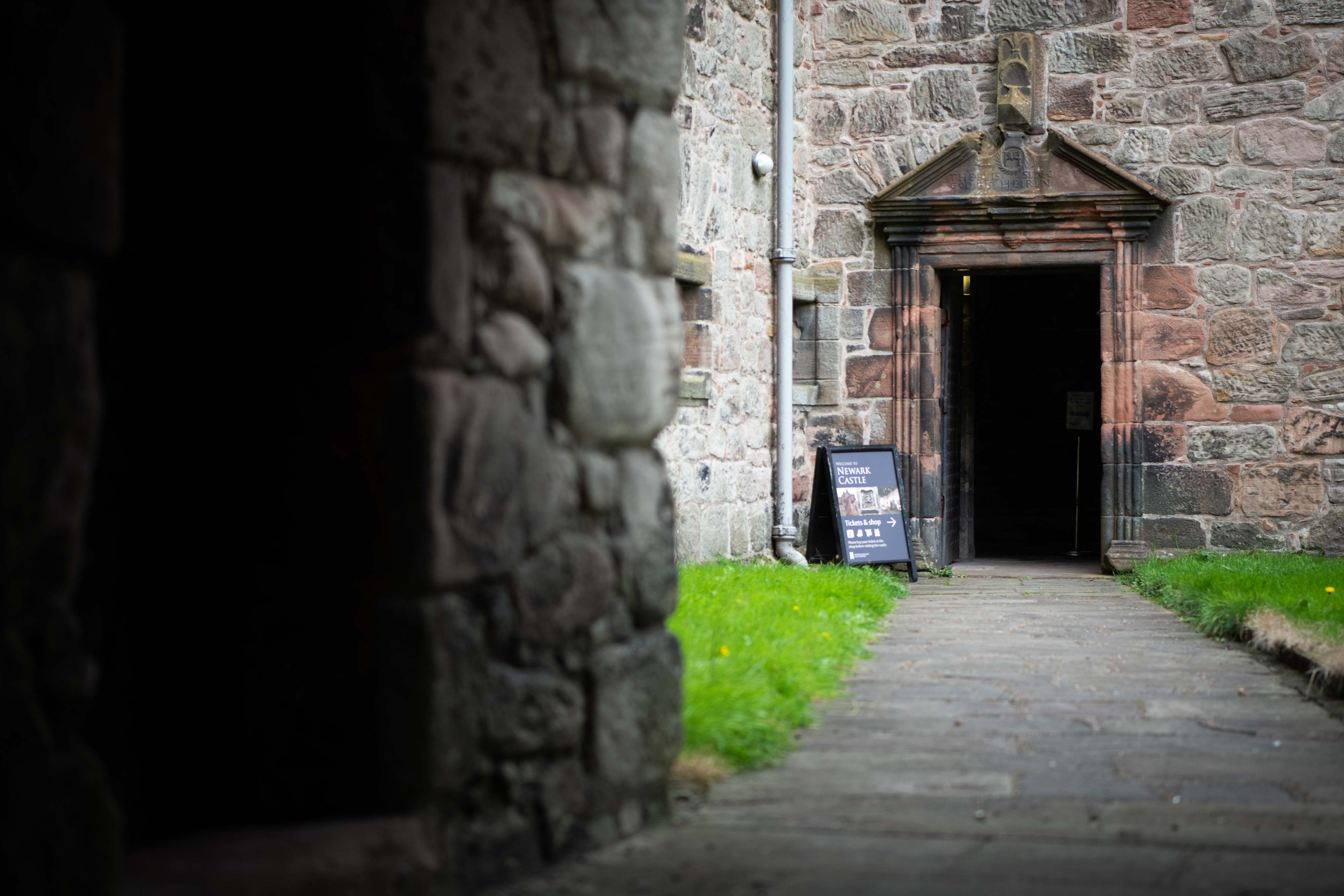 The entrance doorway to a sandstone castle, with a welcome board for visitors beside the door