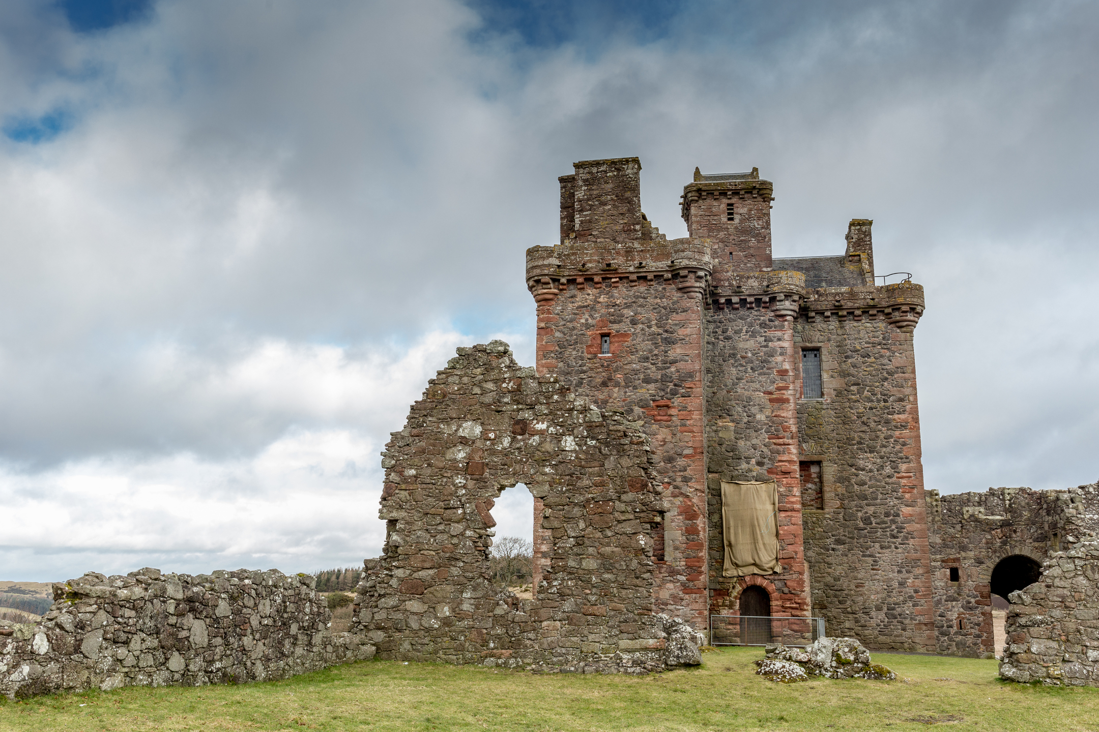 A side view of Balvaird Castle showing its tall stone tower and adjacent ruins