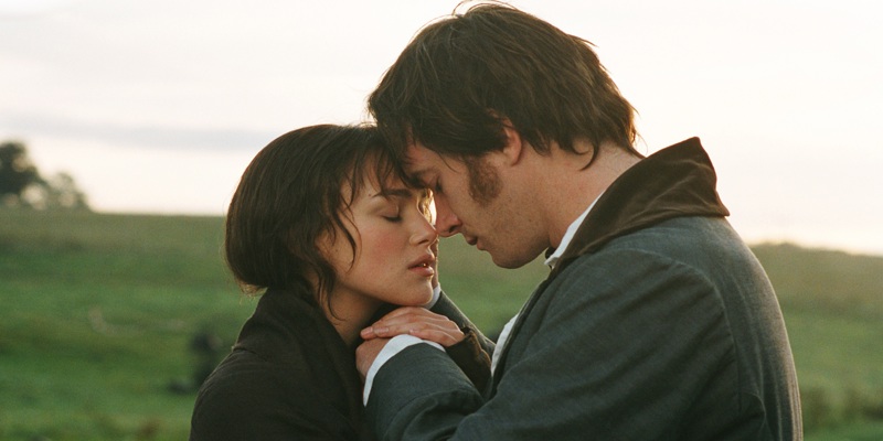 A still from the Pride and Prejudice film showing Mr Darcy and Elizabeth Bennet as they embrace. They stand in a green field and the sun shines behind them.