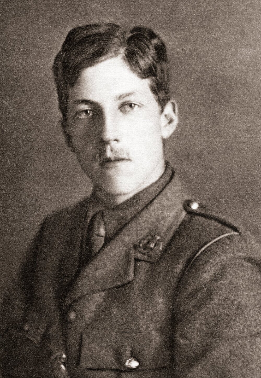 A person with a small moustache and wearing a soldier's uniform looking at the camera.