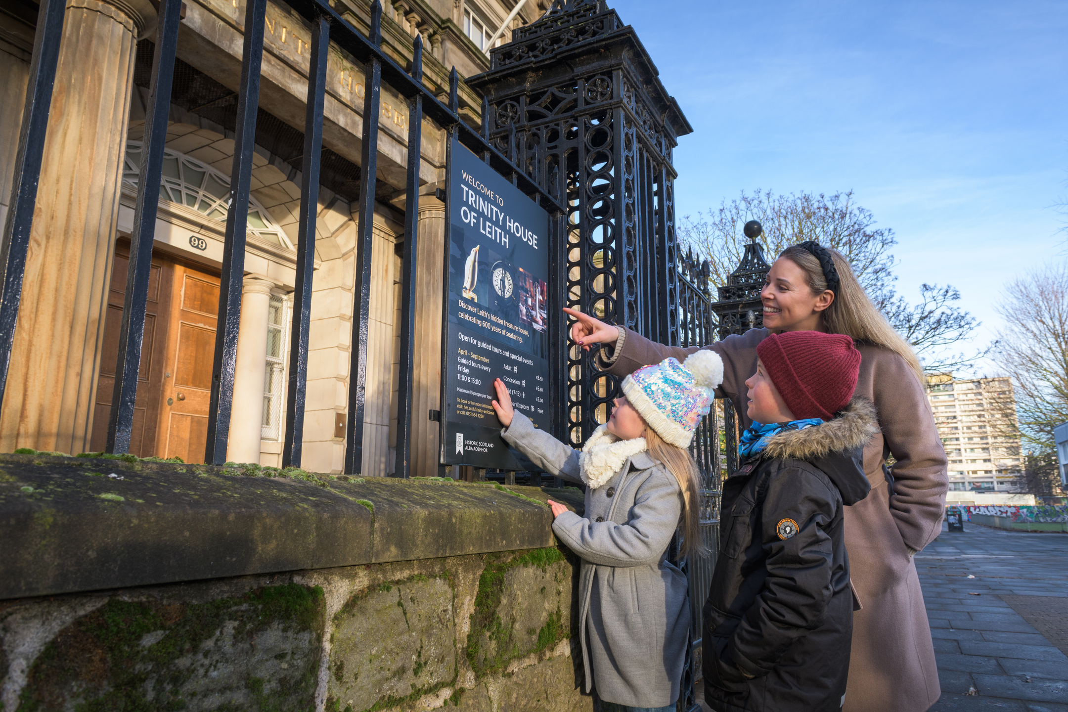 A family point to a sign fixed to metal railings outside a historic tourist attraction