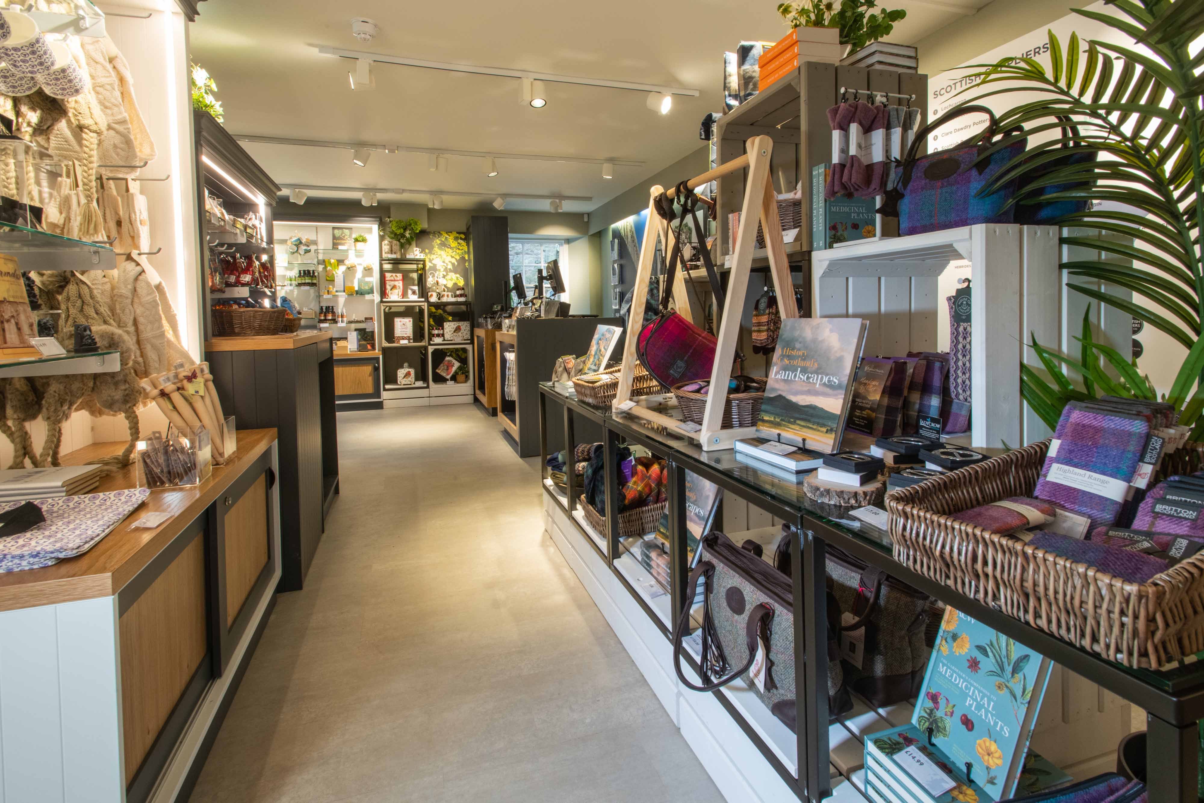 A shop with products lining the walls including books, bags and tartan products 