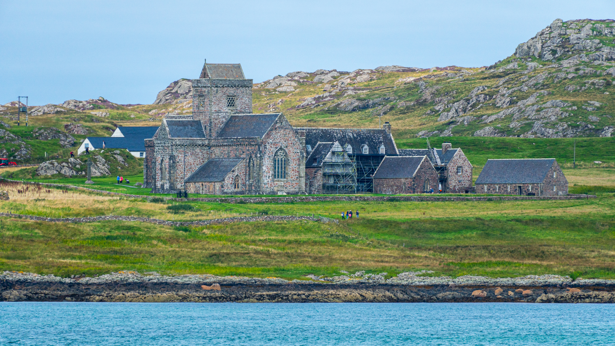 A large, slate roofed historic stone abbey complex behind the sea