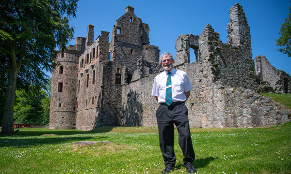 Steward, Douglas McKenzie, standing in the grounds of Huntly Castle