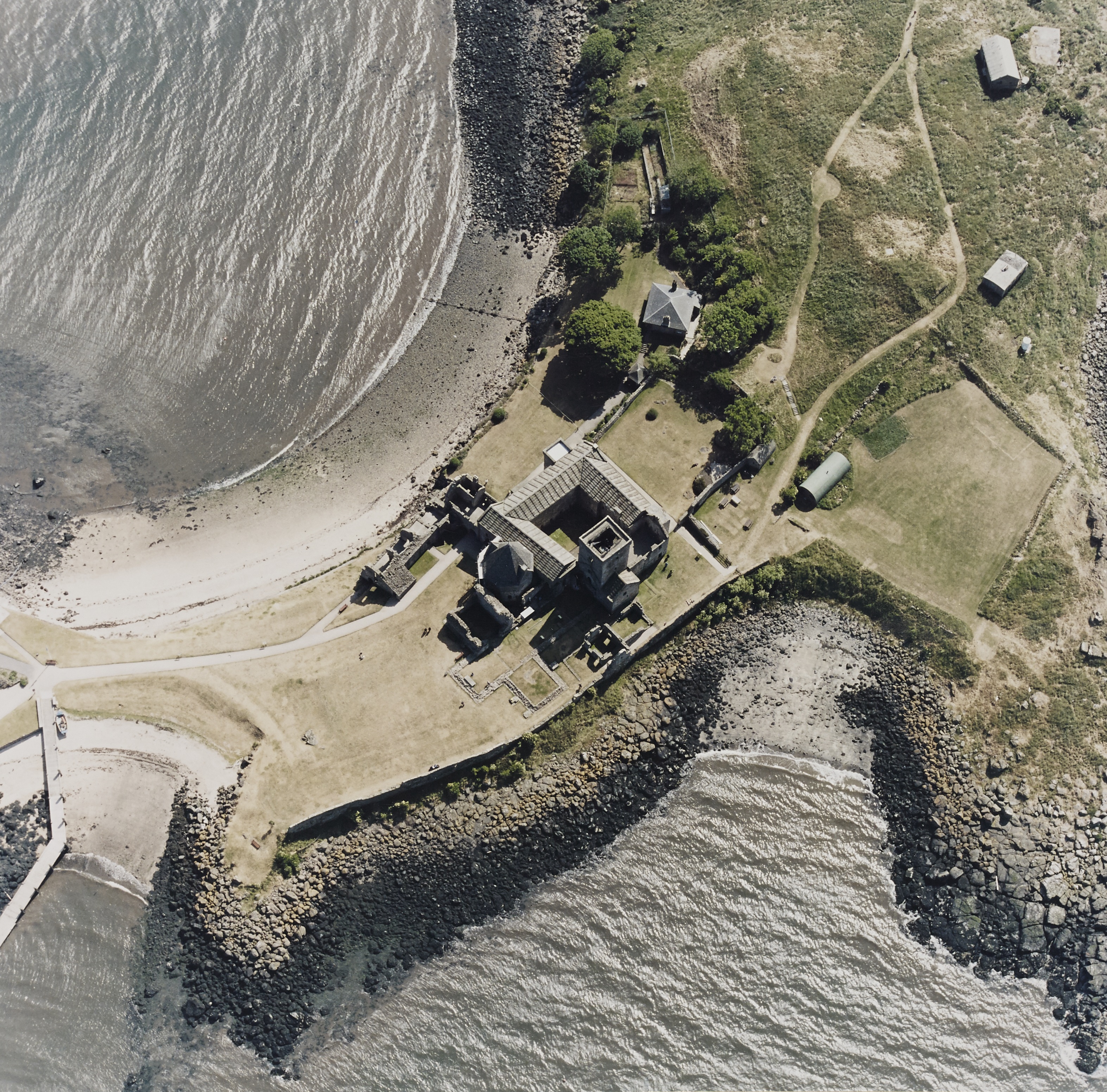 A view from above inchcolm abbey, showing the square-shaped abbey and thin strip of land it is on surrounded by the sea