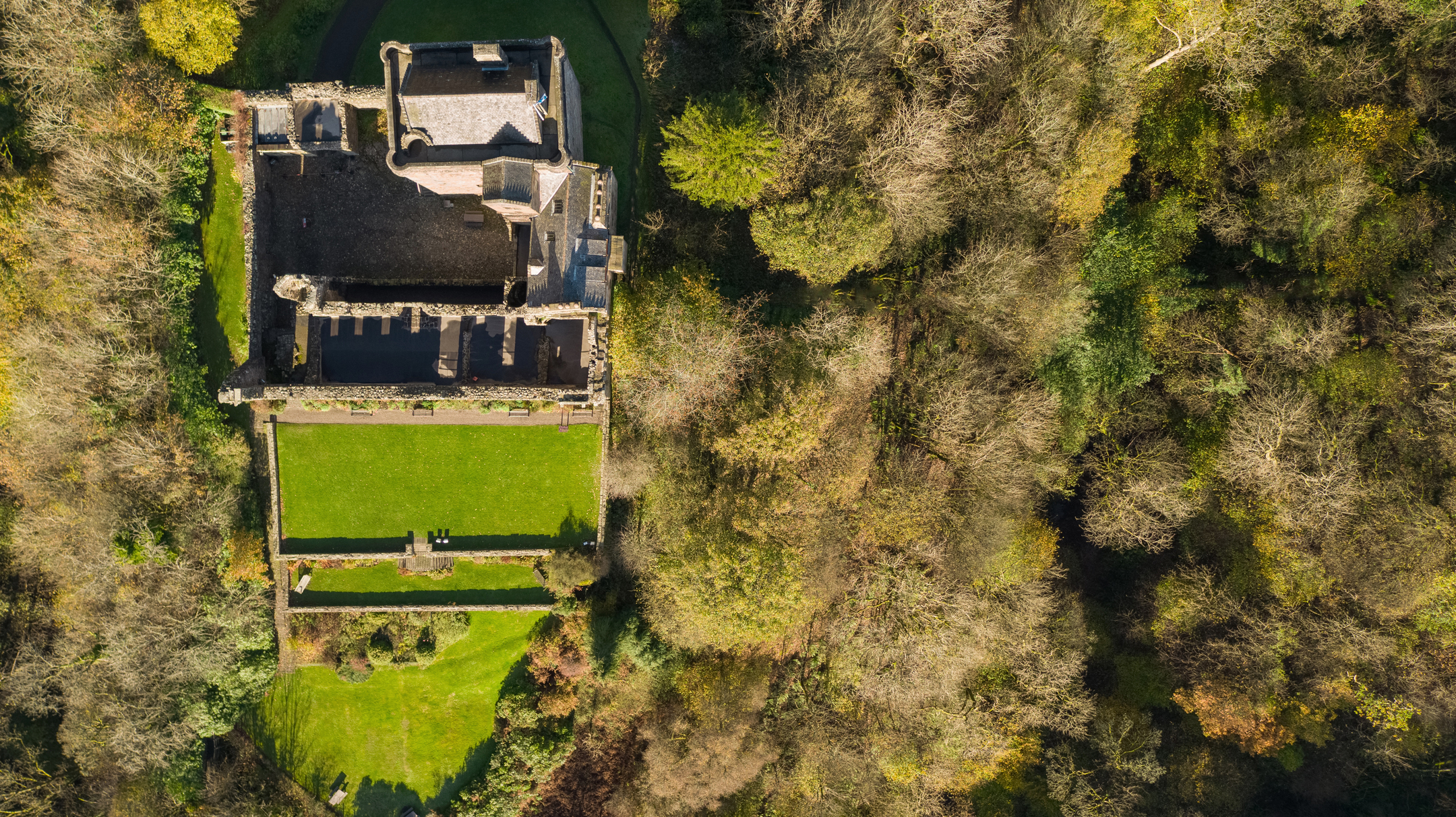 Aerial image of Castle Campbell from the drone directly hovering over the site. You can also see the yellowing trees surrounding the site. 