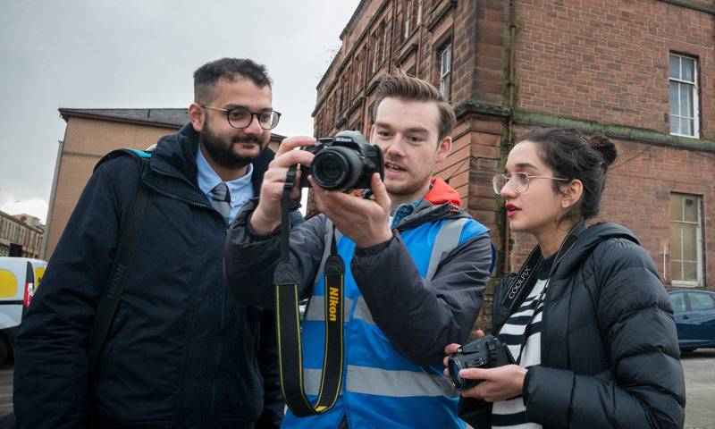 Three people looking at the camera the person in the middle is holding