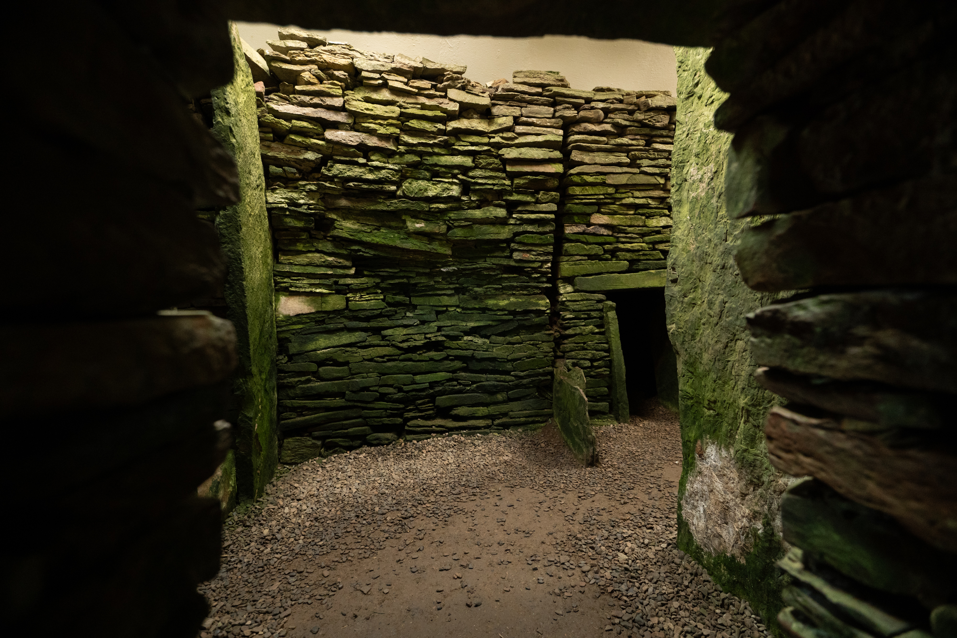A dark chamber with mossy drystone walls 
