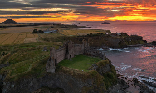 Aerial view of Tantallon Castle, with its distinctive red sandstone curtain wall, and a beautiful late summer sunset 