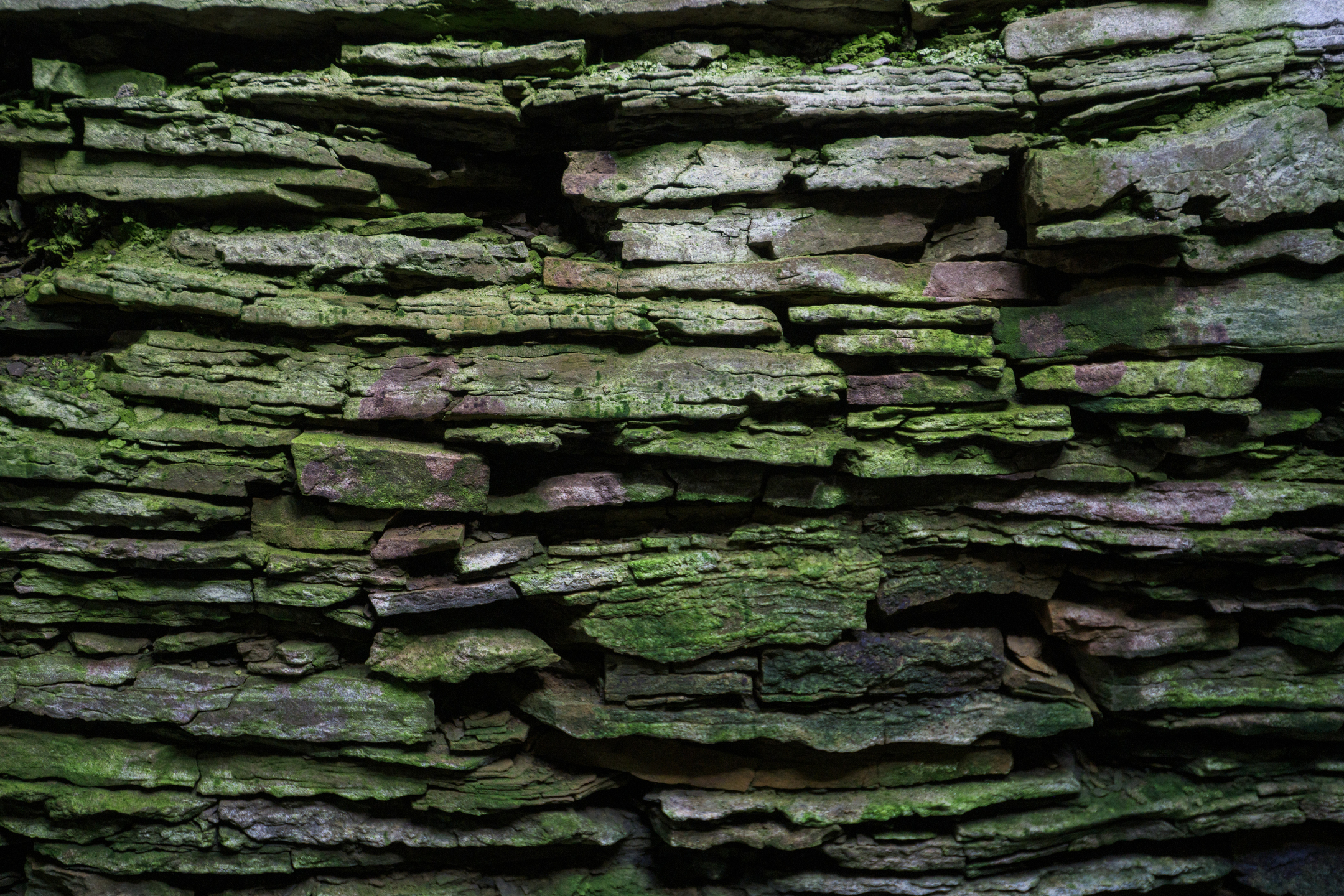 A close-up shot if a wall in a chambered cairn. Flat, lichen-covered stones have been stacked on top of each other to create an ancient-looking but clearly very sturdy structure.