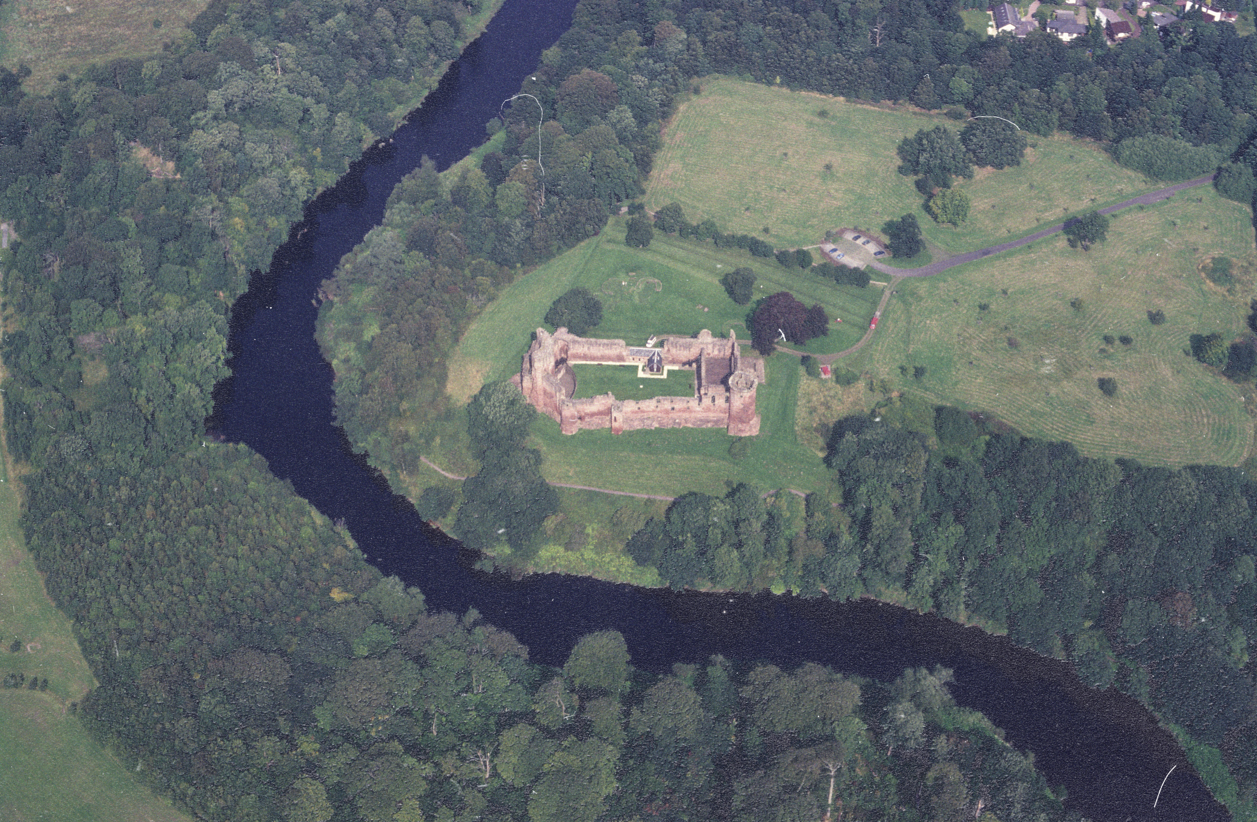 Aerial view of castle ruin that sits in the bend of a river