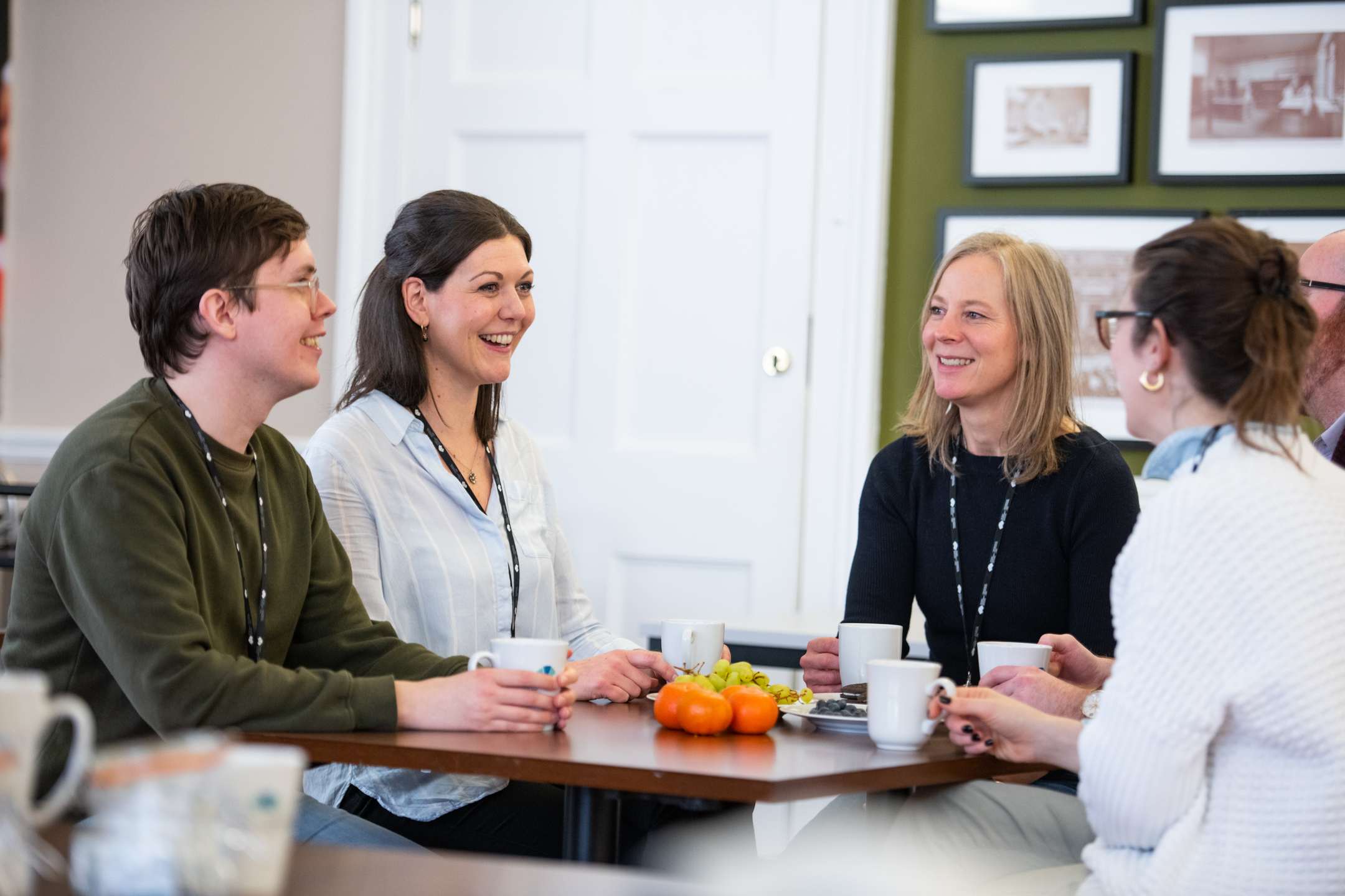 A group of five employees sat talking around a table in a cafeteria. 