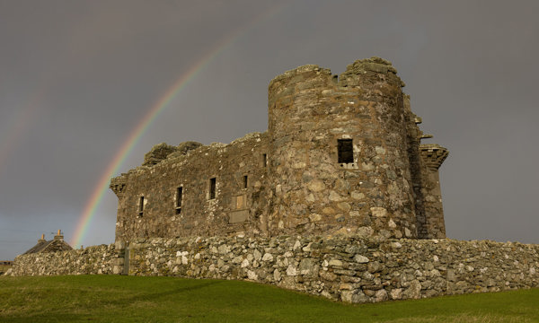 A historic monument with a grey sky and imposing rainbow