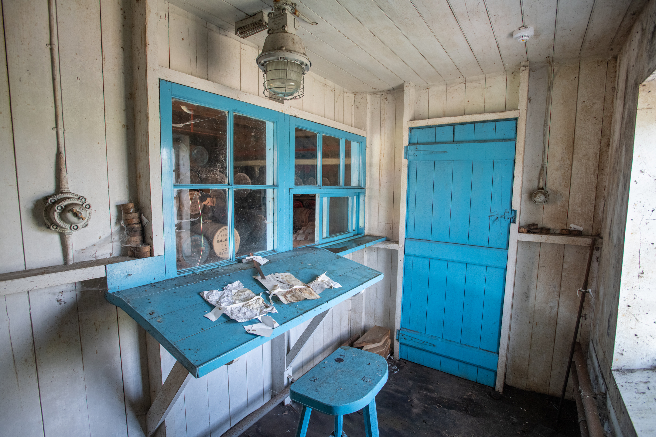 Preserved office space at Dallas Dhu distillery featuring a blue wooden desk, matching door and window frame, with historic fixtures.