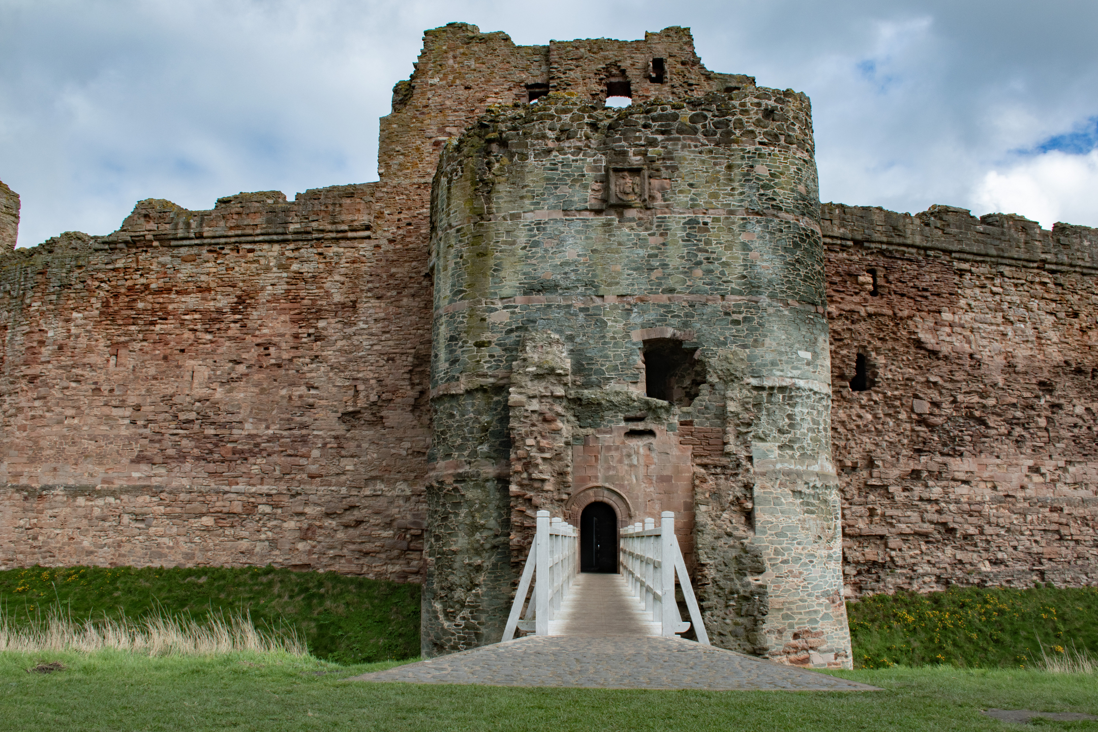 View directly towards entrance of substantial castle ruin with white bridge leading to the entrance