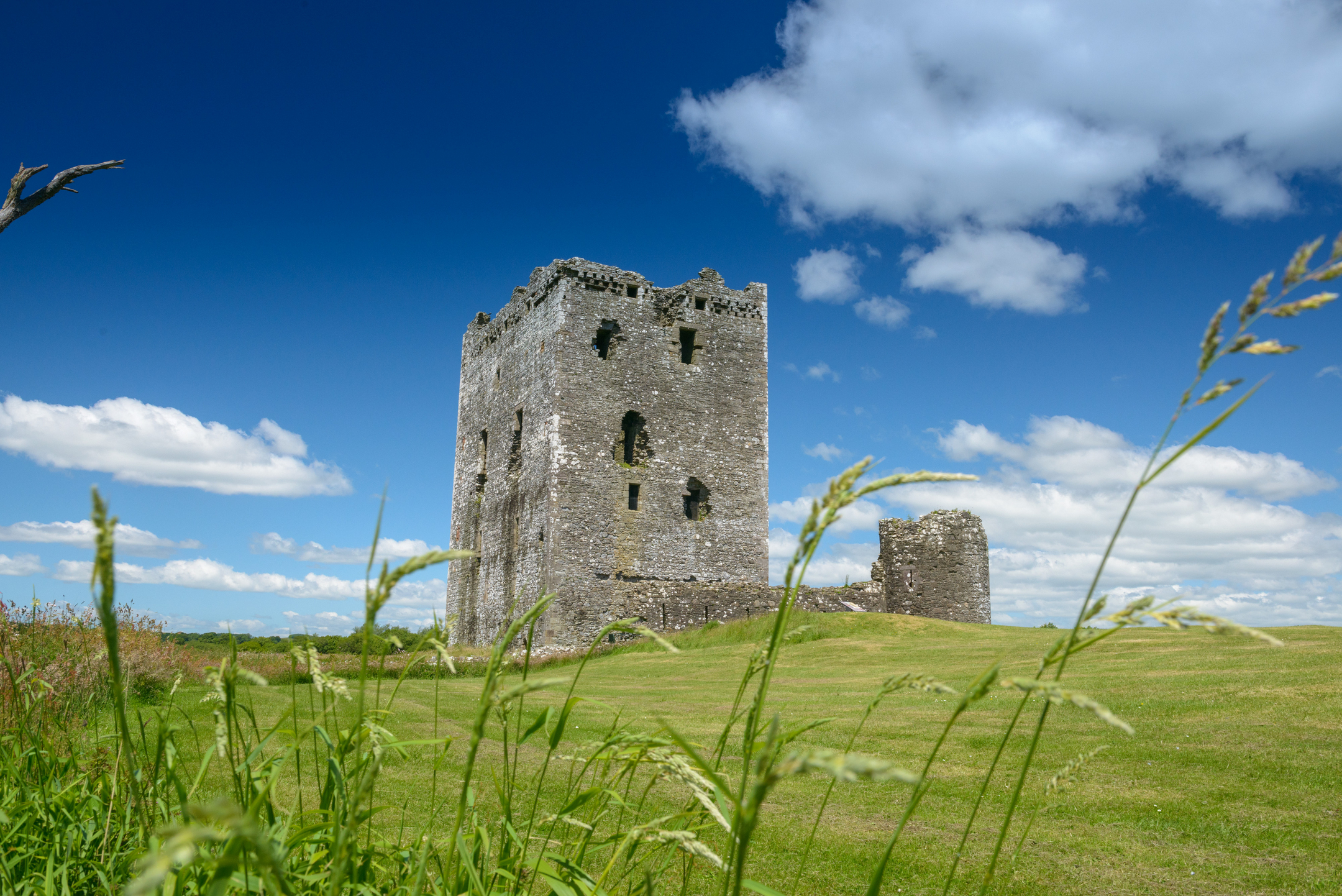 Ruined stone castle tower on a grassy hill