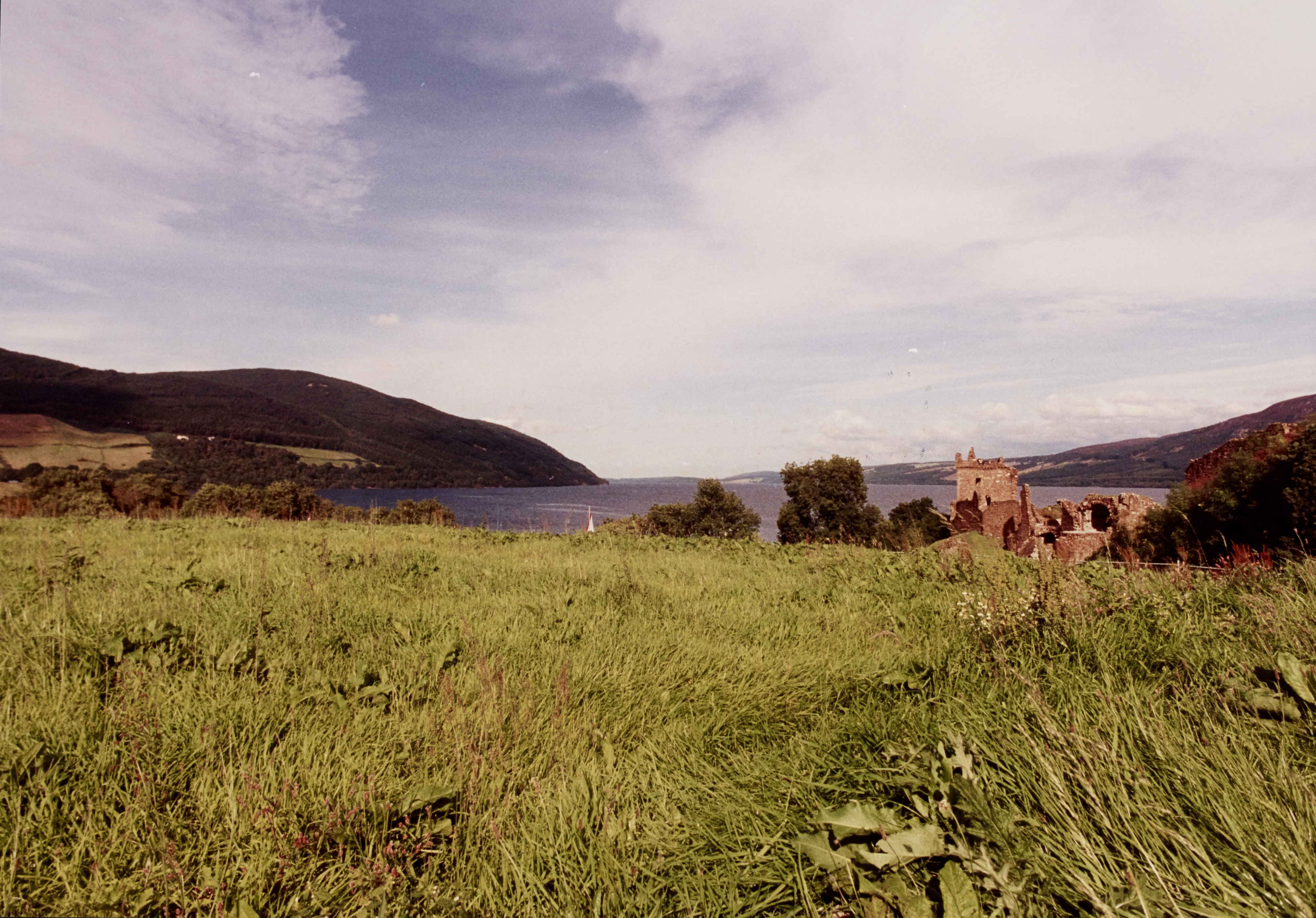 View across grassy area towards Urquhart Castle and Loch Ness beyond