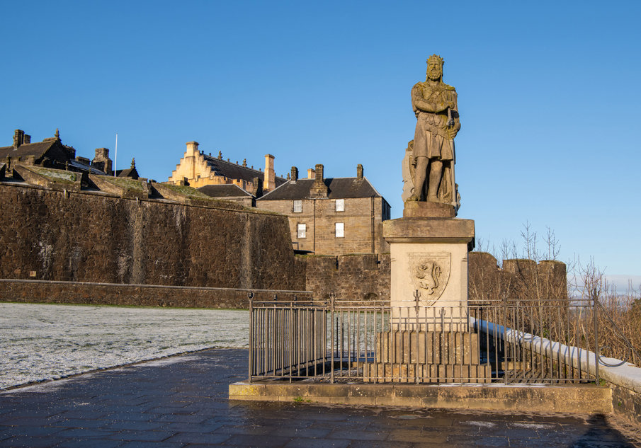 Robert the Bruce statue outside Stirling Castle with sprinklings of snow over the grass
