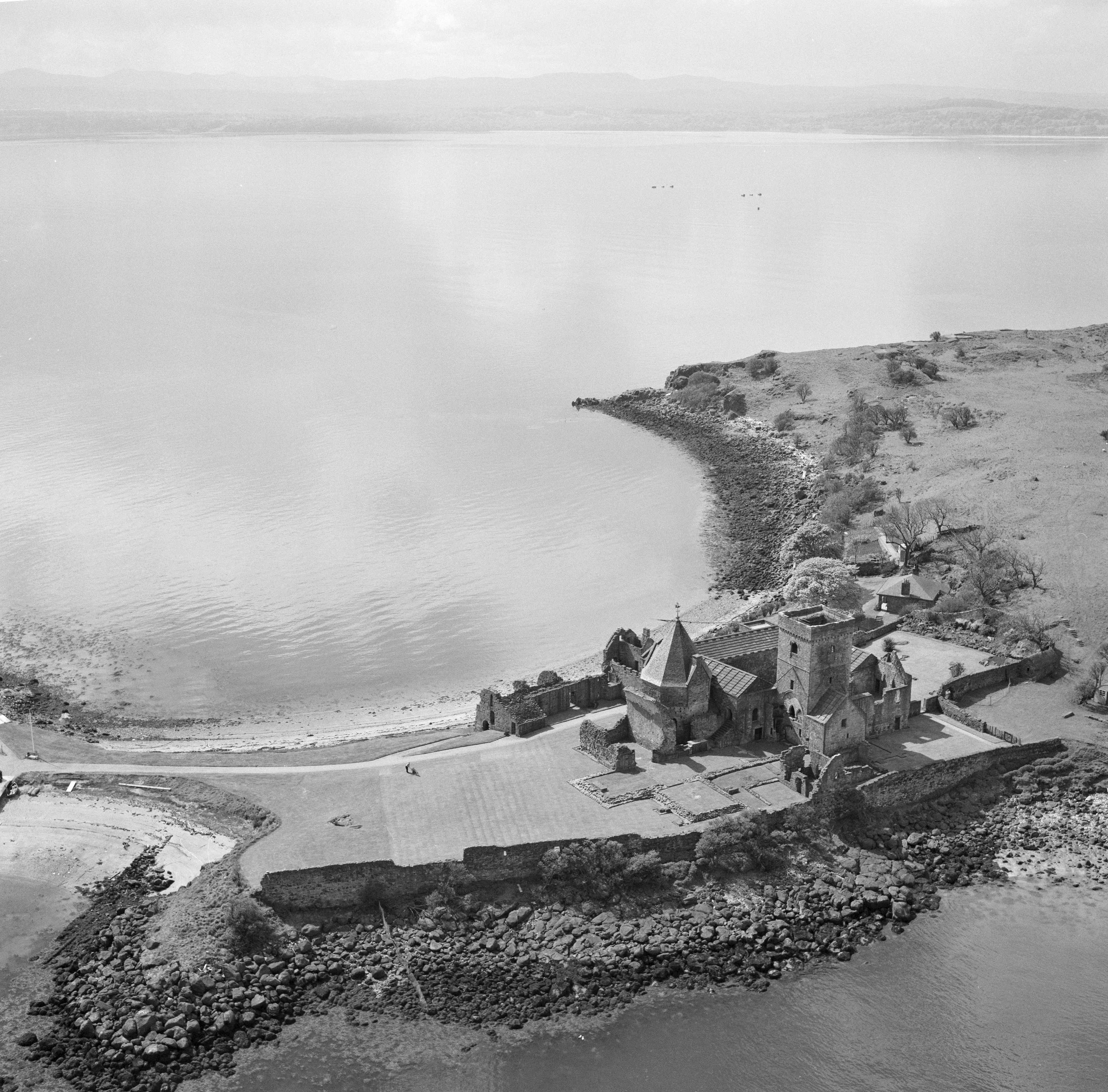 A view from a plane of a large historic stone abbey o a small strip of land on a small island