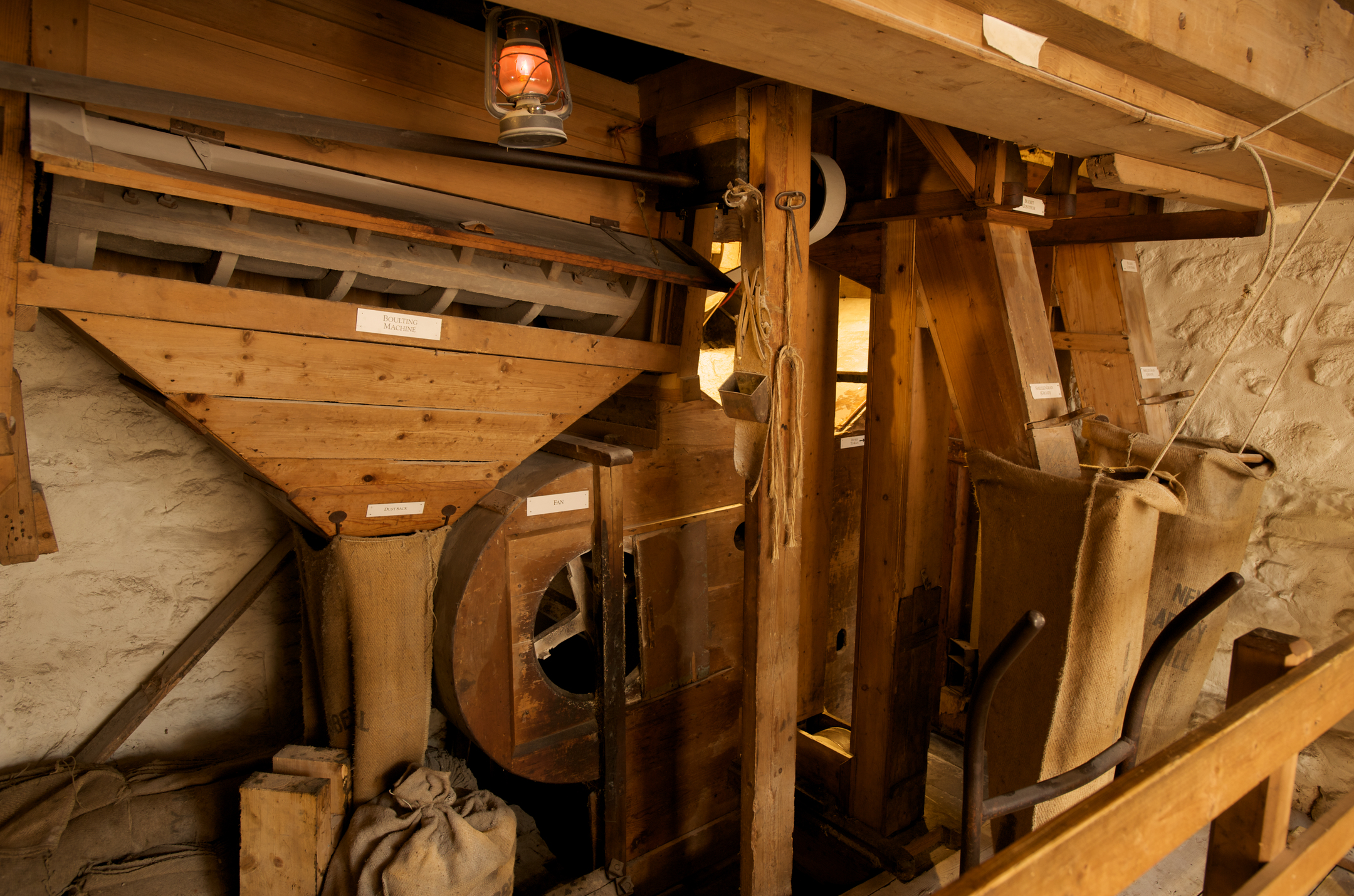 Wooden machinery, mechanisms, brown sacks and a hung lit lantern.