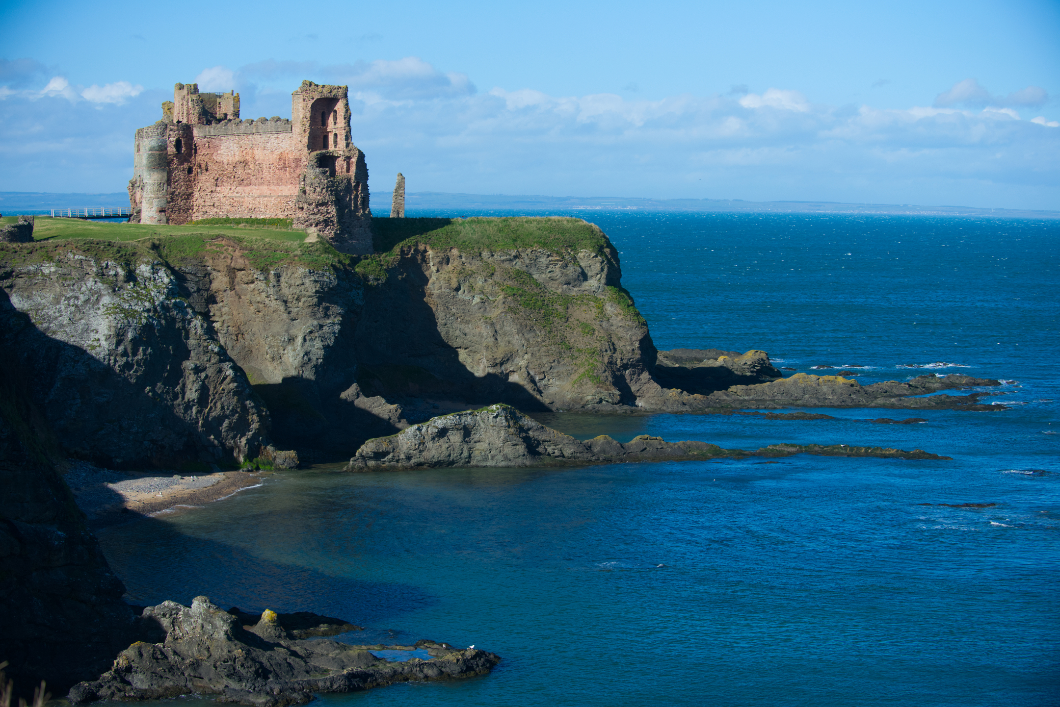 View of Tantallon Castle from down the coast, showing the castle perched close to the cliffside