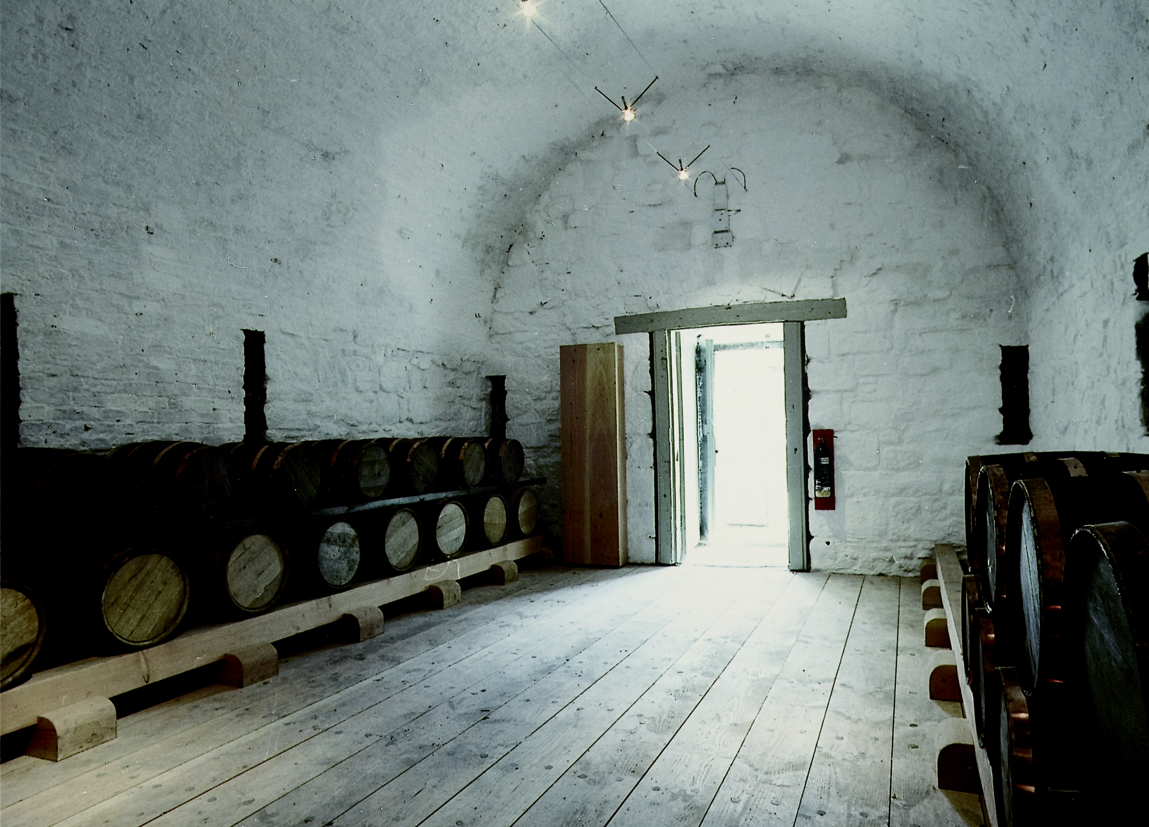 Inside a store room at Dumbarton Castle with white walls and a curved ceiling, and barrels stored on either side