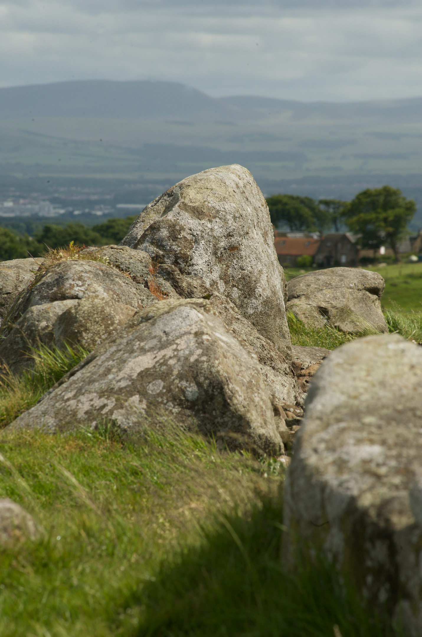 Rocks in a grassy hilltop area with further hills in the distance