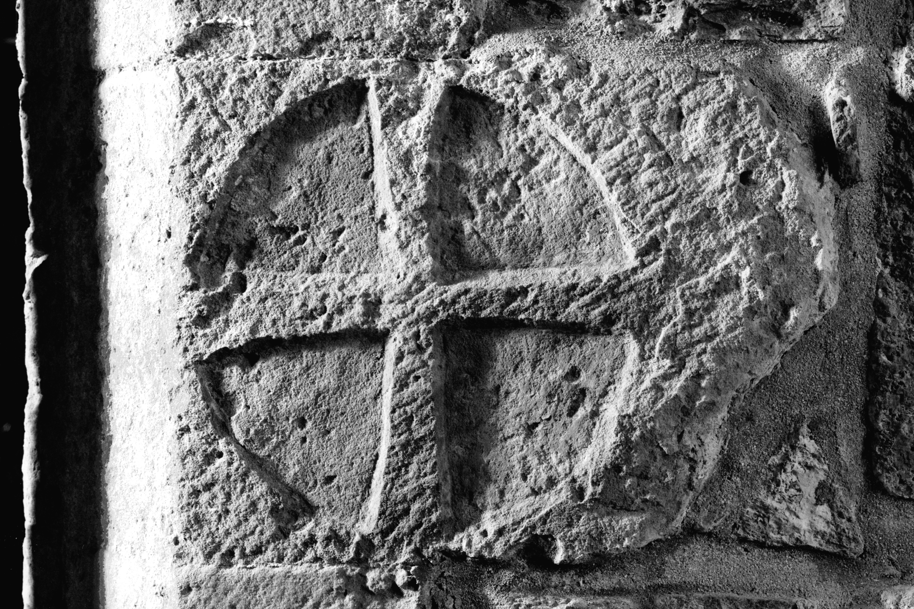 A cross inside a circle, carved into a weathered block of stone 