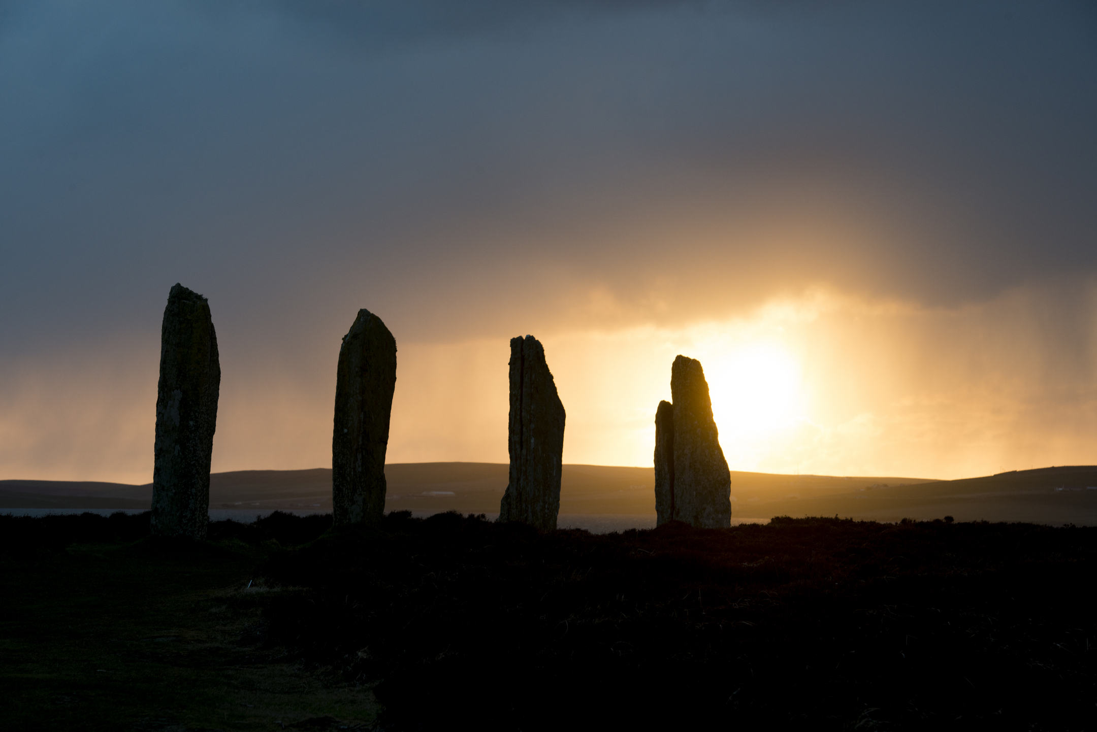 A row of four large standing stones silhouetted against the evening sky. The stones become slightly smaller in height moving from left to right, adding a satisfying element to the photo. 