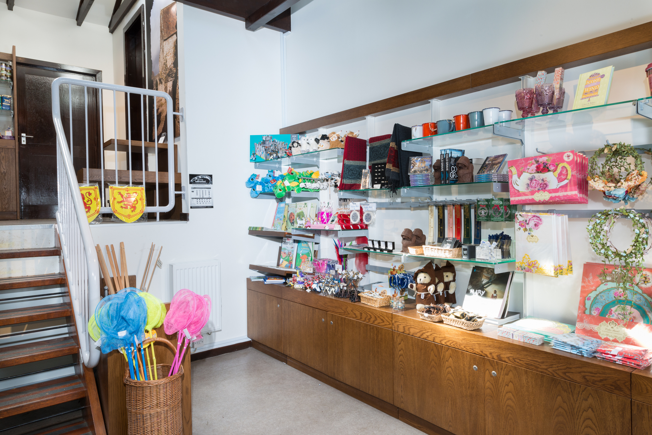 The interior of a gift shop with shelves of mugs, books, toys, and souvenirs.