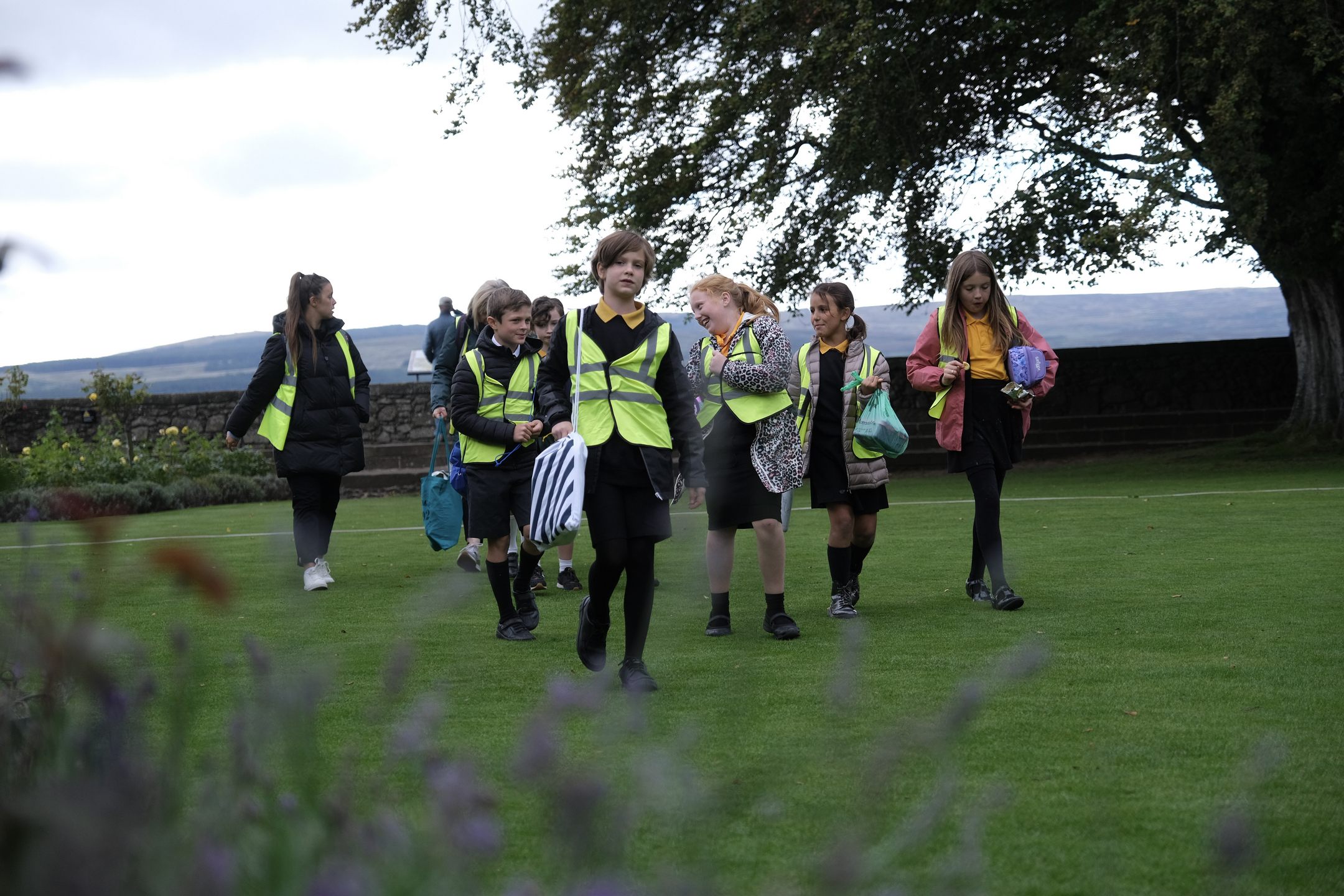 School pupils in hi-viz vests in garden area of castle