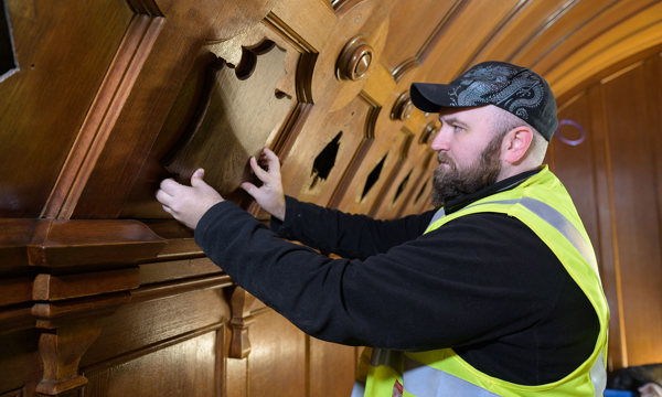 An HES apprentice joiner wearing a high vis jacket and working with wood