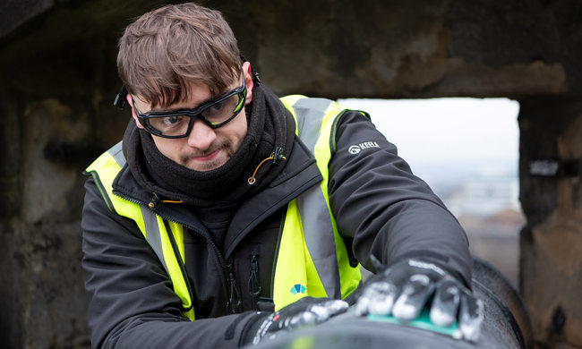 A man wearing a high vis jacket and safety glasses working on a cannon
