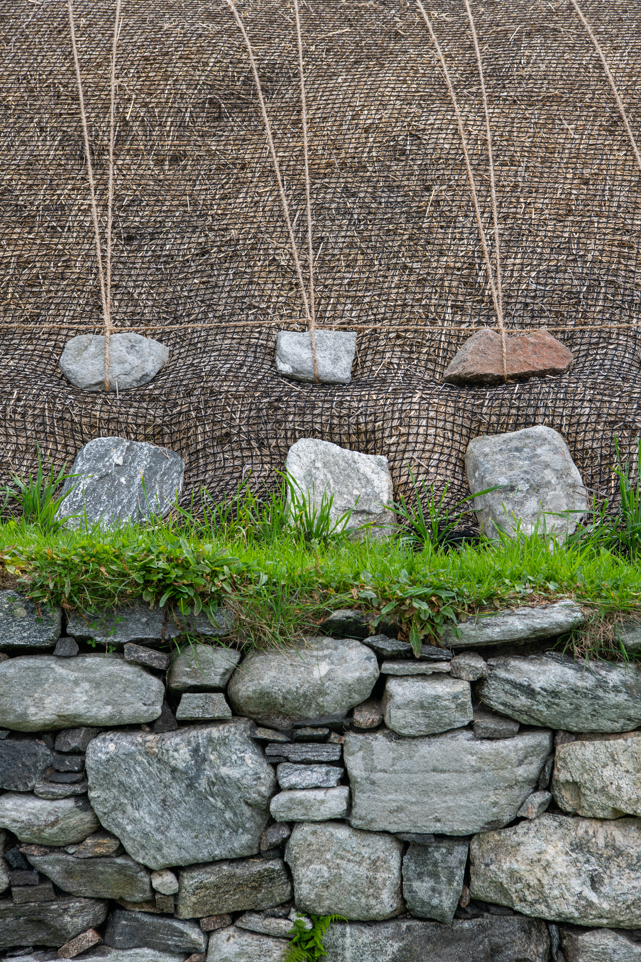 A thatched roof, weighed down with stones and ropes 