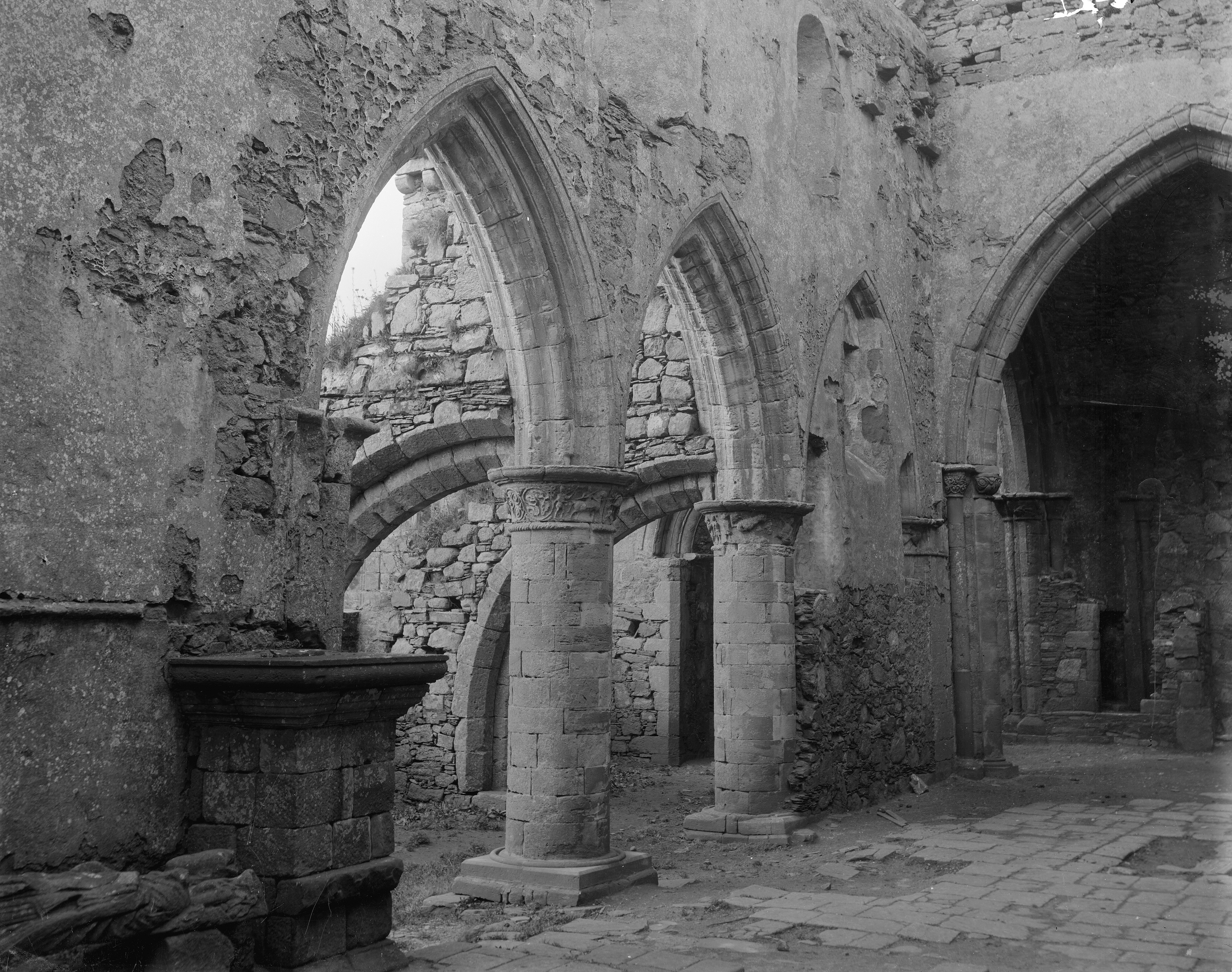 Two stone archways with columns, inside a historic, partially ruined, abbey building