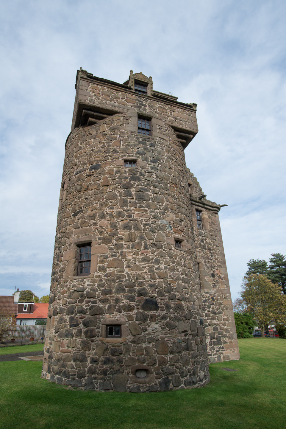 A stone, round tower. There are small windows in the tower.