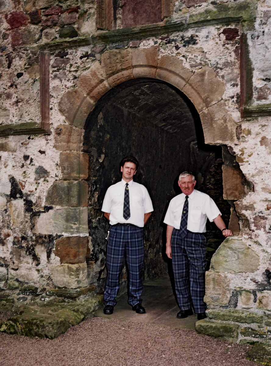 Two men in tartan trousers standing in archway