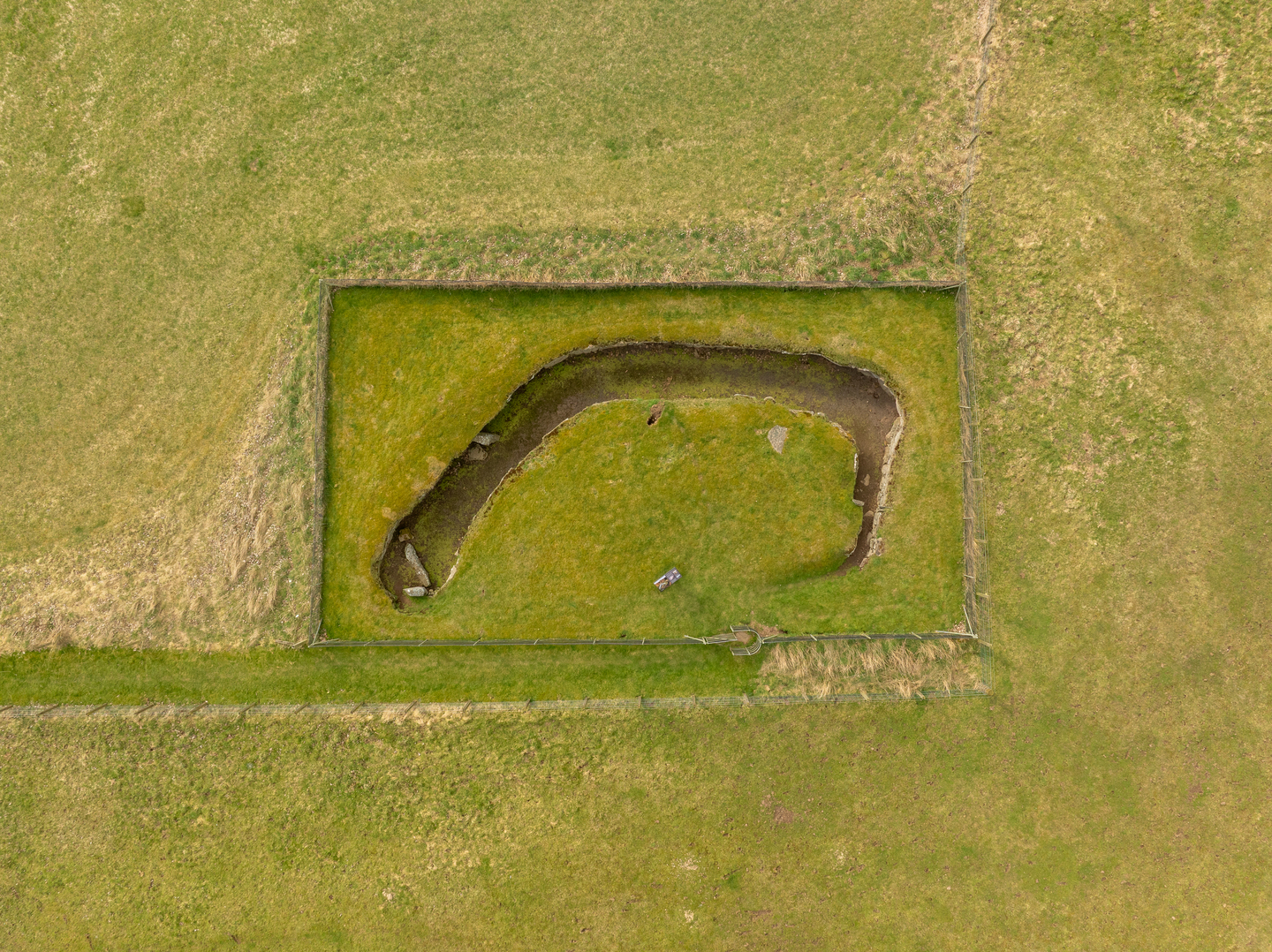 A long banana-shaped passage on the ground of a field. It is surrounded by a marked rectangle. 